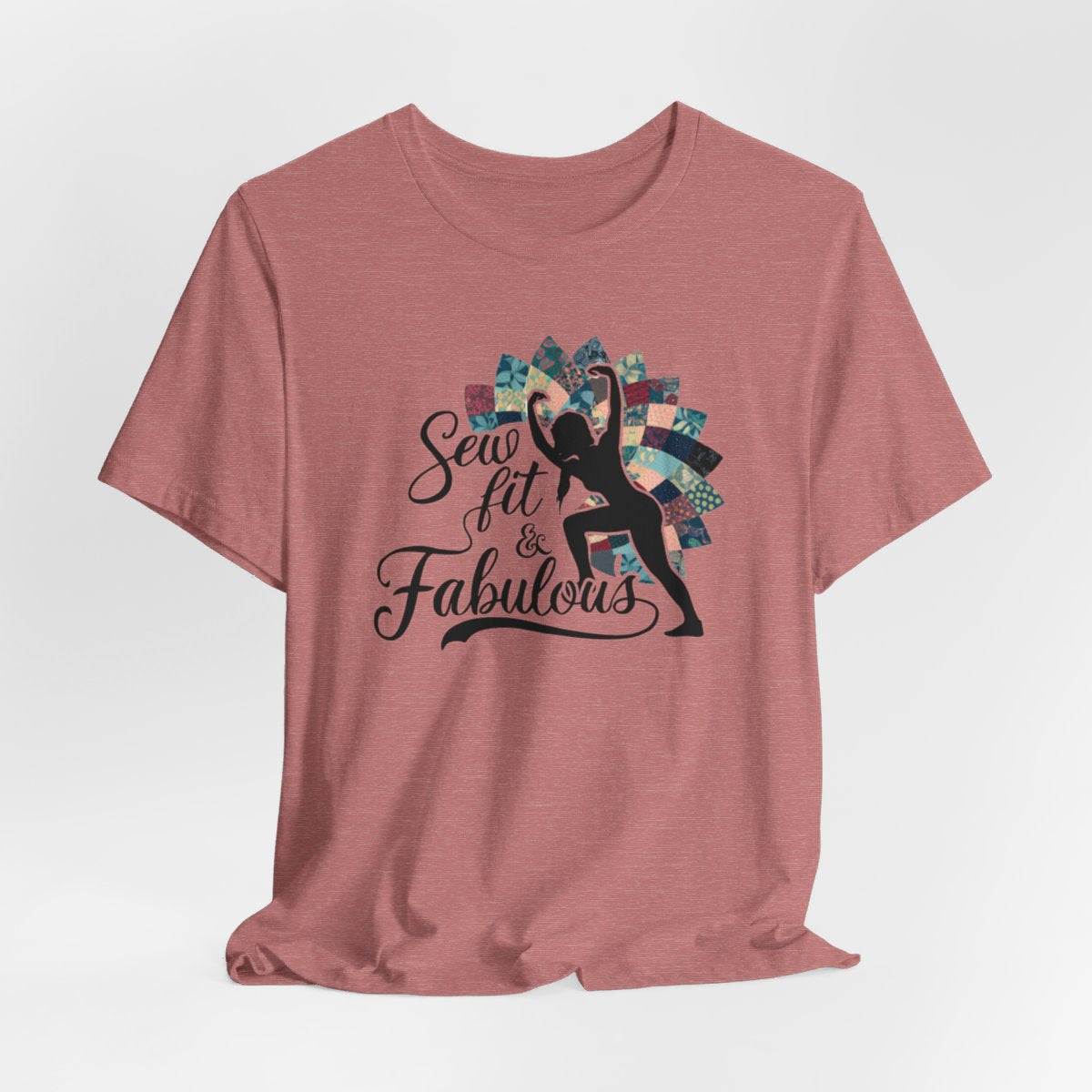 A Heather Mauve T-Shirt featuring a black silhouette of woman with raised arms against colorful patchwork background. Text reads "Sew fit & Fabulous" in stylized script.