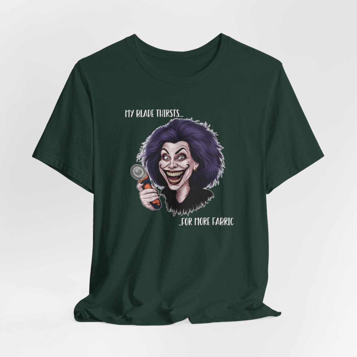 A Forest T-shirt showing a cartoonish character with wild purple hair and an exaggerated grin, holding a rotary cutter. Text reads "My blade thirsts... for more fabric", humorously depicting a quilter's endless desire for new materials.
