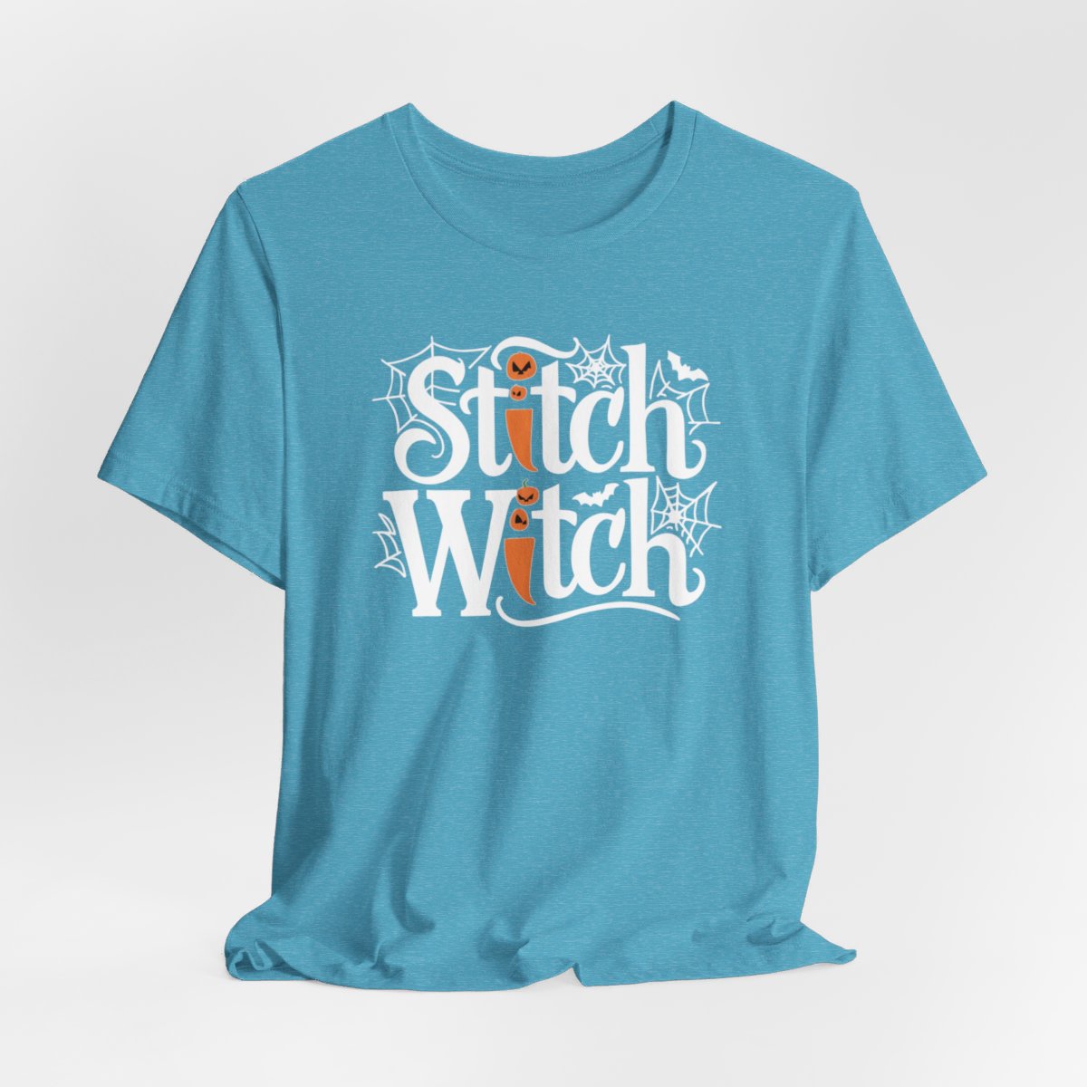 T-shirt design with "Stitch Witch" text in Halloween-themed typography. Jack-o'-lanterns, spiderwebs, and bats decorate the letters. The "i" in "Stitch" resembles a sewing needle. Ideal for quilters who love Halloween.