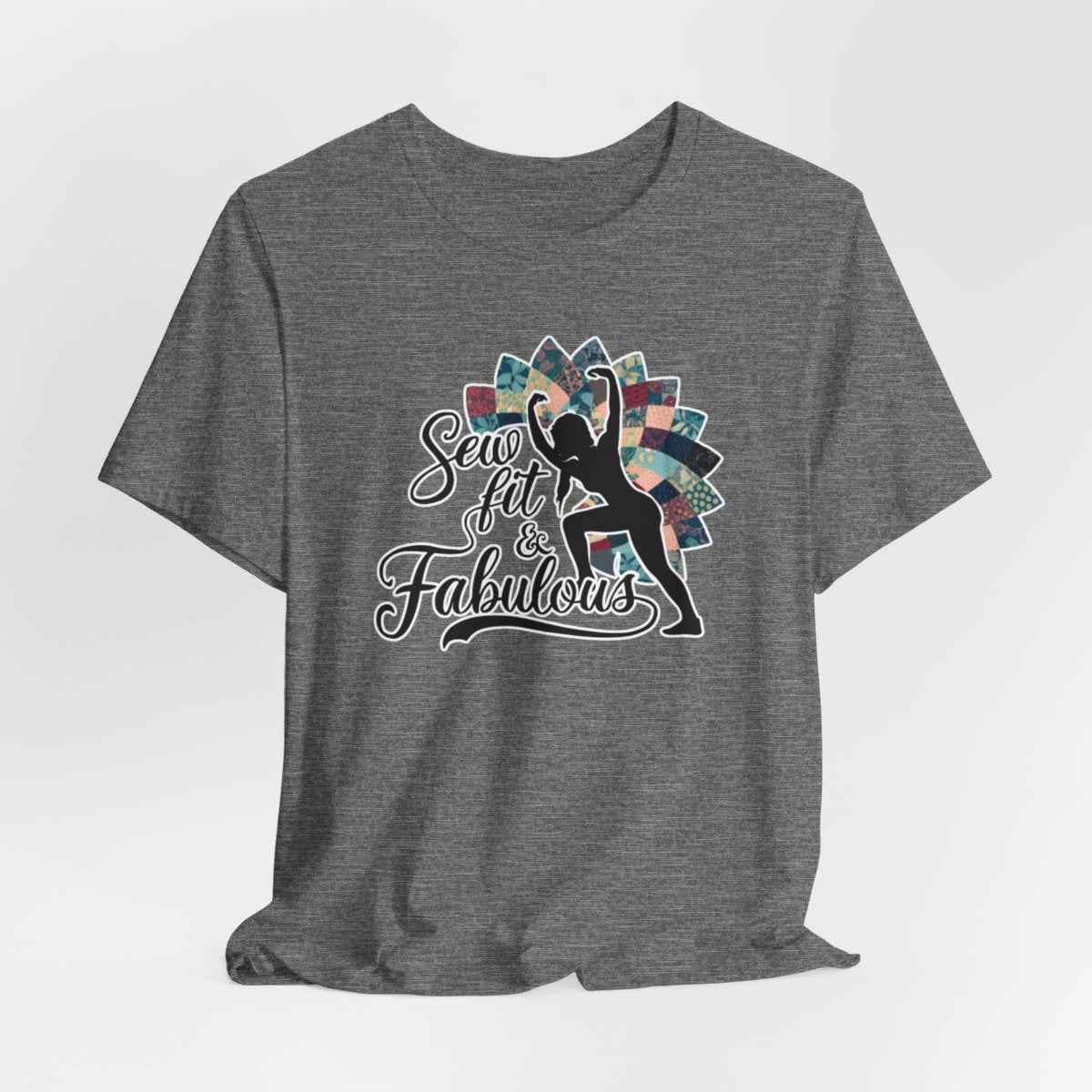 A Deep Heather T-Shirt featuring a black silhouette of woman with raised arms against colorful patchwork background. Text reads "Sew fit & Fabulous" in stylized script.