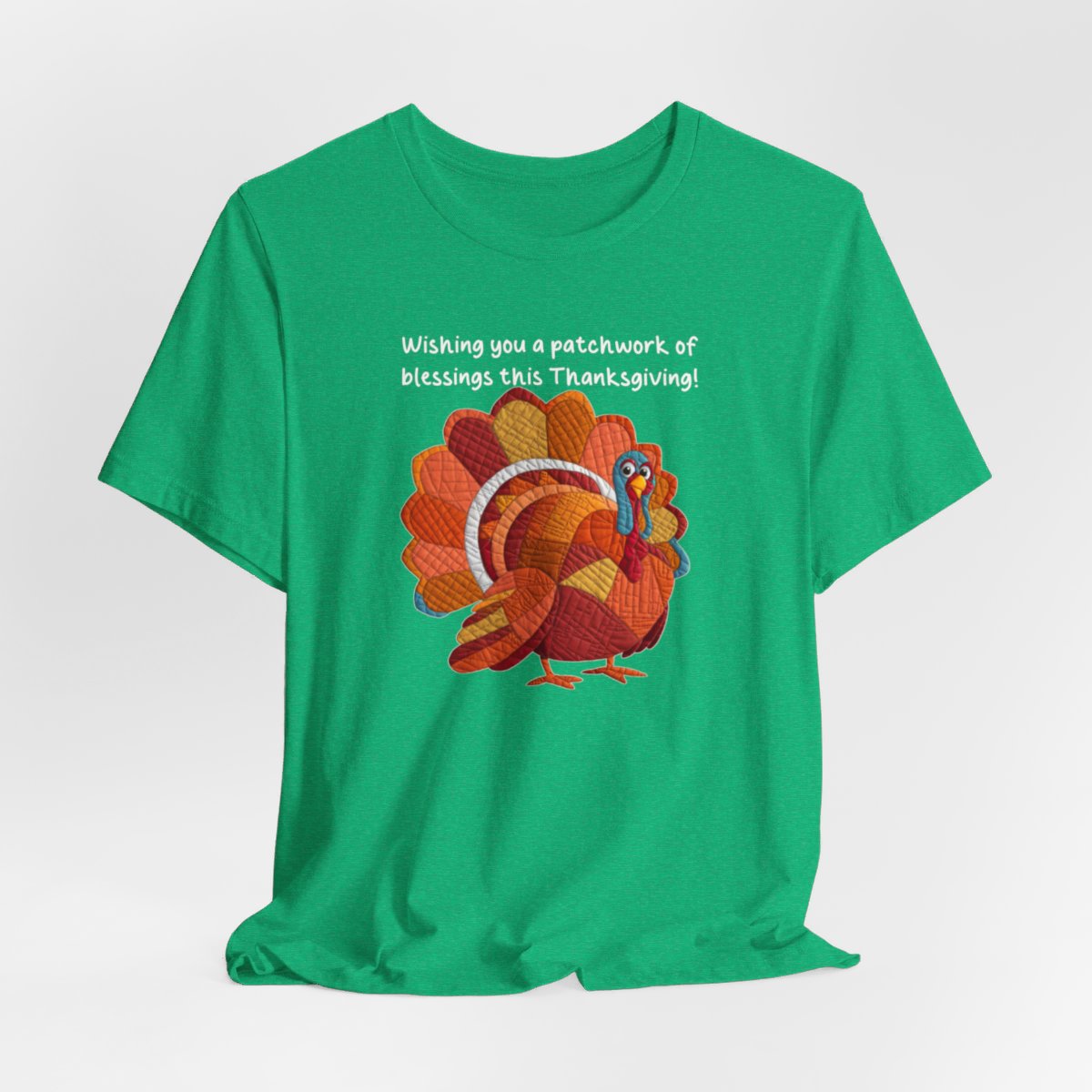 A Heather Kelly thanksgiving quilting t-shirt featuring a quilted patchwork turkey in autumn colors with text "Wishing you a patchwork of blessings this Thanksgiving!" Turkey features various quilt patterns and textures in shades of orange, red, yellow, and blue. Whimsical, crafty holiday design perfect for quilting enthusiasts.