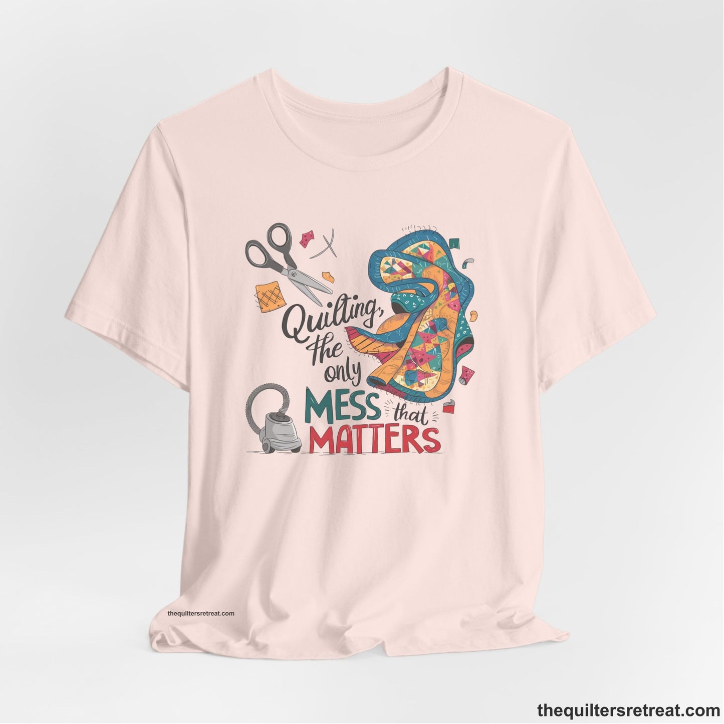 A Soft Pink Short Sleeve T-Shirt with a quilting tools and patchwork pieces with bold "Quilting, the only mess that matters" text