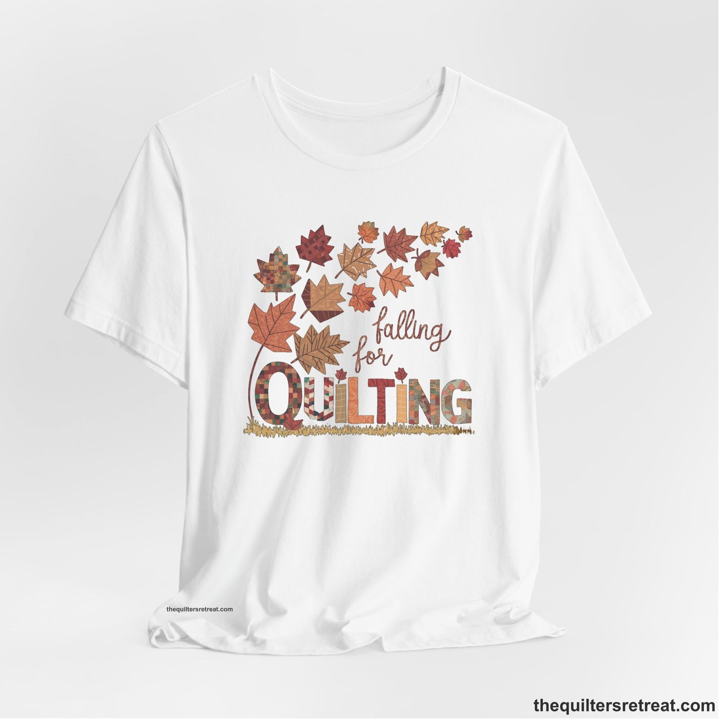 A White Short Sleeve T-Shirt with a falling autumn leaves and "Falling for Quilting" text in a patchwork style