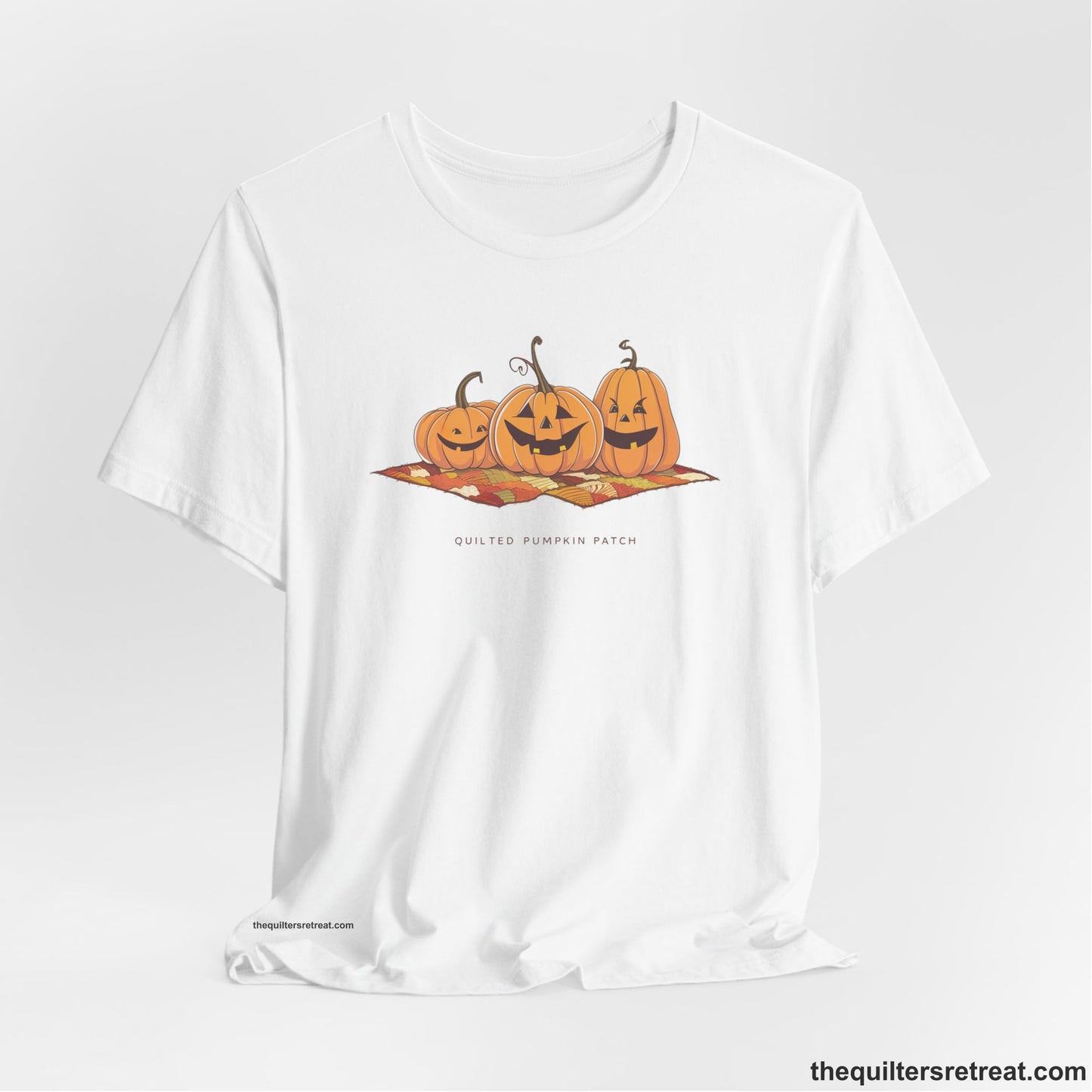 A White Short Sleeve T-Shirt with a playful jack-o'-lantern trio on a quilt with "Quilted Pumpkin Patch" text