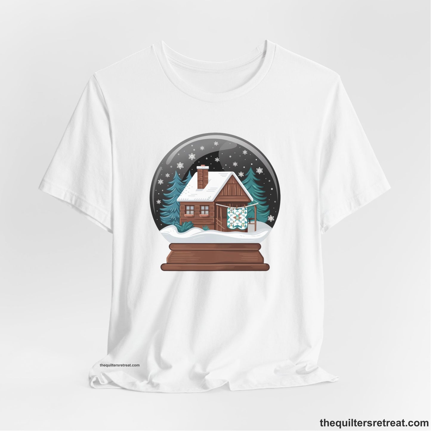 A White Short Sleeve T-Shirt with a cabin in a snow globe with snowflakes and trees, in a cozy rustic style