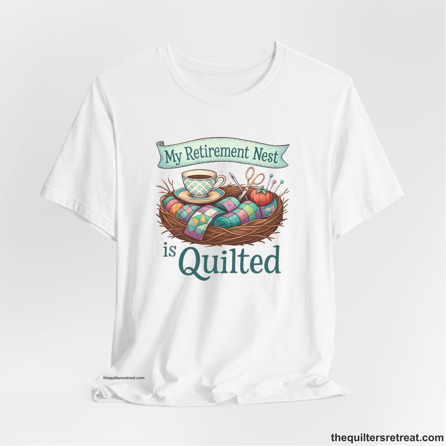 A White Short Sleeve T-Shirt with a My Retirement Nest is Quilted text with a cozy sewing elements illustration