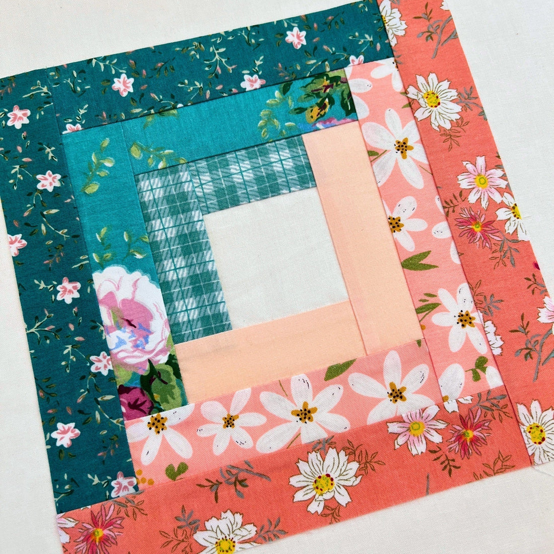 A finished Log Cabin block sewn from several prints that still read clearly as a light half and a dark half
