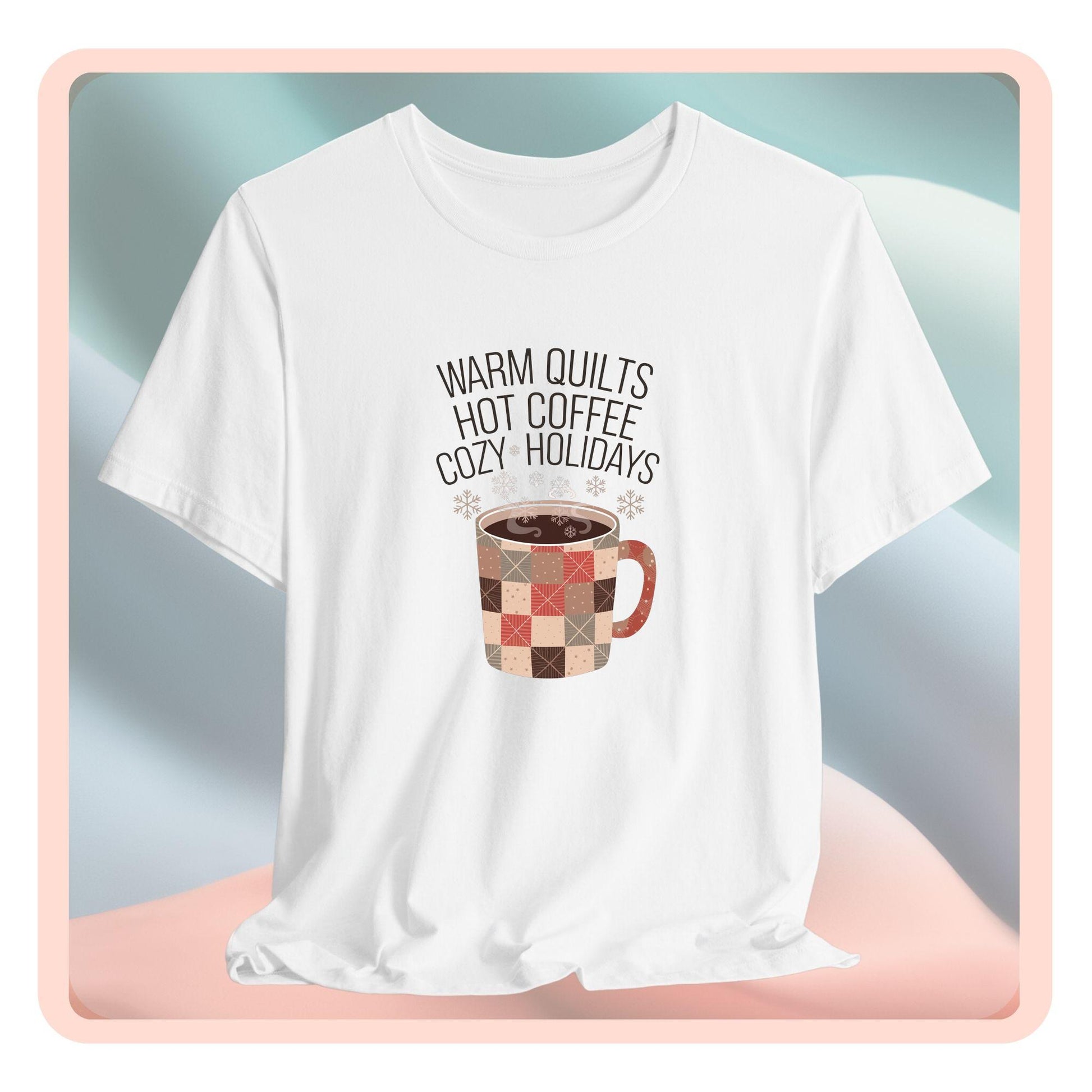 A christmas quilting t-shirt featuring a cozy patchwork quilt-themed coffee mug, surrounded by snowflakes, with the phrase "Warm Quilts, Hot Coffee, Cozy Holidays" above the mug, celebrating the warmth of quilts and coffee during the holiday season.
