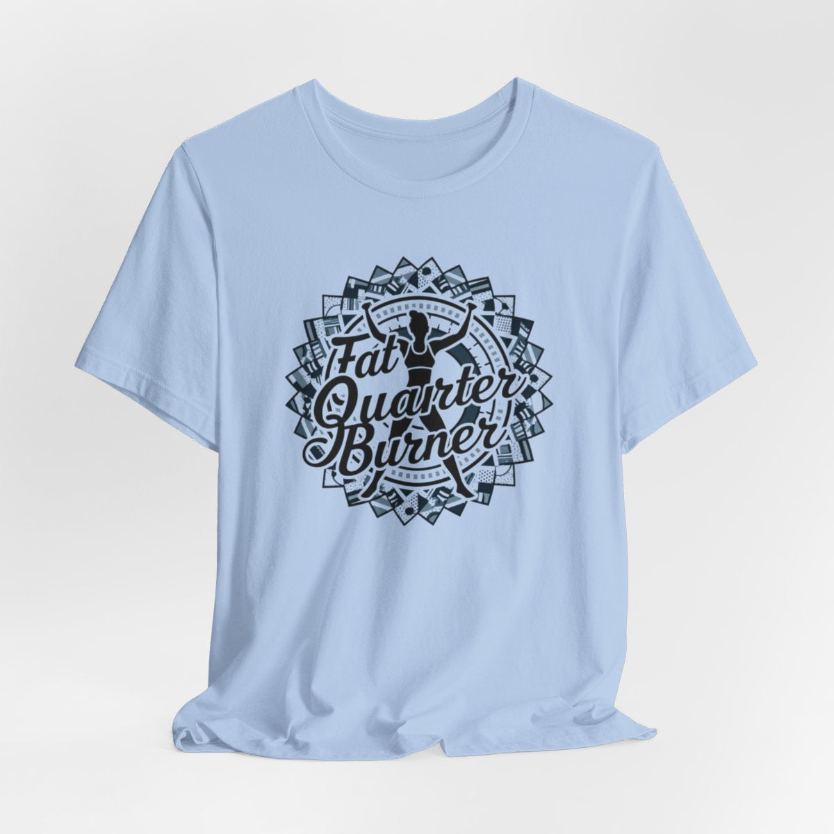 A Baby Blue T-Shirt featuring a patchwork border surrounding silhouette of woman lifting weights. Text reads "Fat Quarter Burner" in bold script.