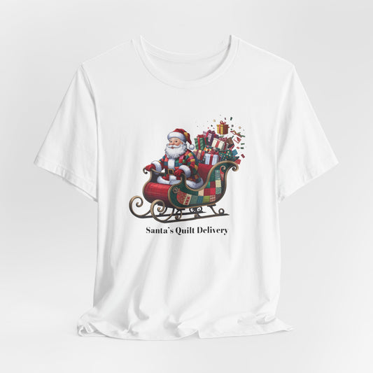 A christmas quilting t-shirt featuring Santa Claus wearing a patchwork quilt coat, sitting in a sleigh filled with gifts and quilts, with the phrase "Santa's Quilt Delivery" below, combining holiday cheer and quilting fun.