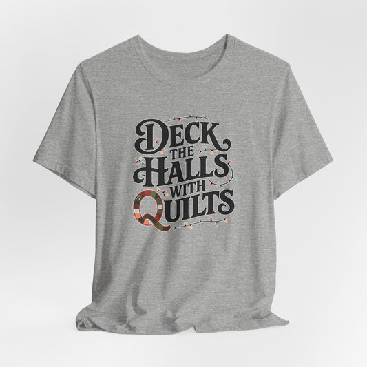 An Athletic Heather christmas quilting t-shirt featuring the phrase "Deck the Halls with Quilts," adorned with holiday lights and quilting-inspired elements, including a quilted 'Q' for a humorous touch.
