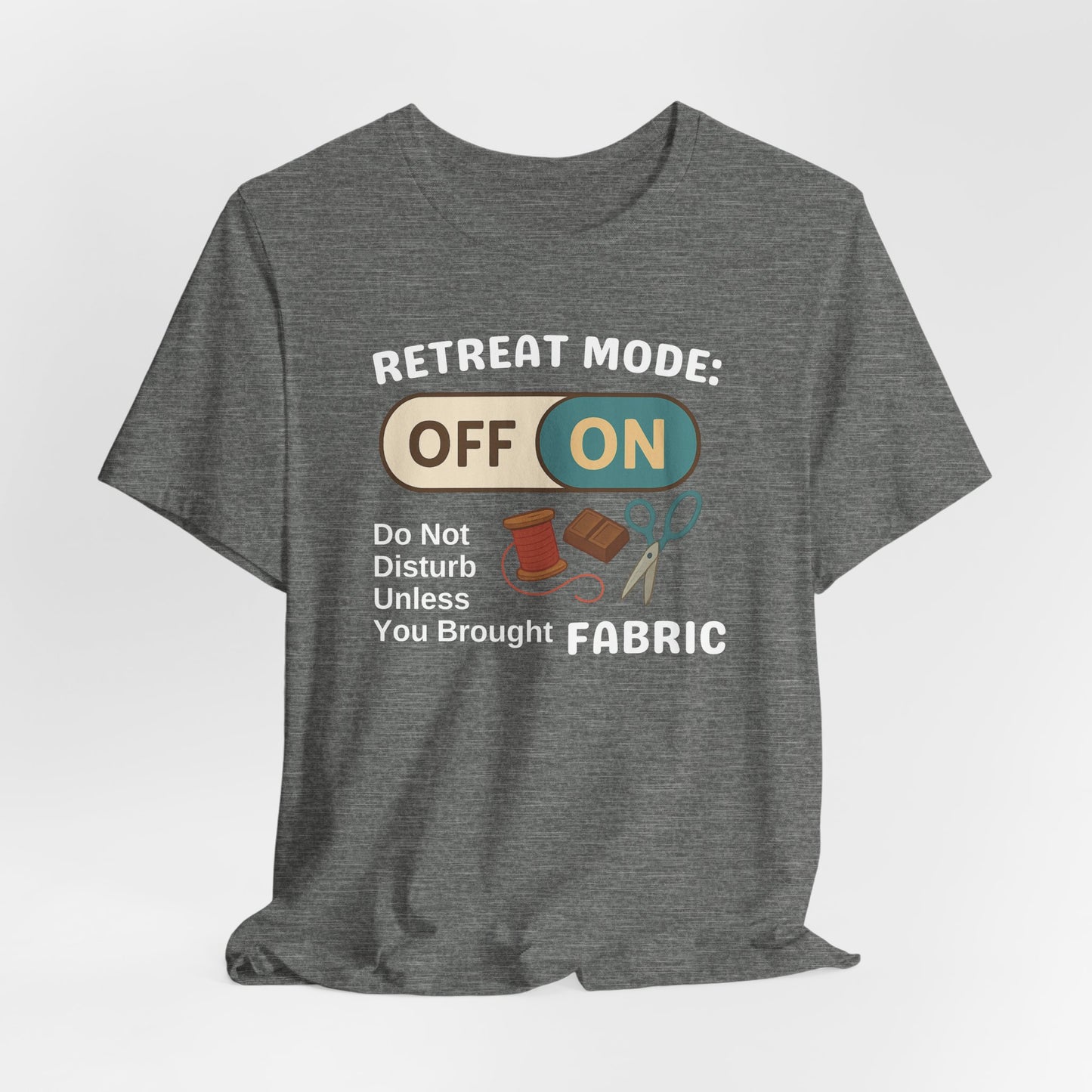 A A Deep Heather t-shirt with a toggle switch that says "Retreat Mode: OFF/ON" surrounded by a spool of thread, chocolate, and scissors. Text below reads "Do not disturb unless you brought fabric." Fun gift for quilting retreats.