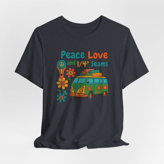 A A Heather Navy t-shirt with colorful retro design showing a peace sign rotary cutter, patchwork van, and text “Peace Love and 1/4" Seams.” Surrounded by flowers made of thread spools. Fun vintage-style quilting shirt.