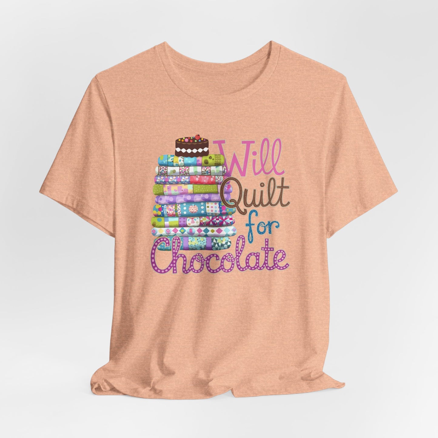 A Heather Peach t-shirt featuring a whimsical design of a colorful stack of quilts topped with a chocolate cake and the phrase 'Will Quilt for Chocolate,' perfect for quilters who love sweets.