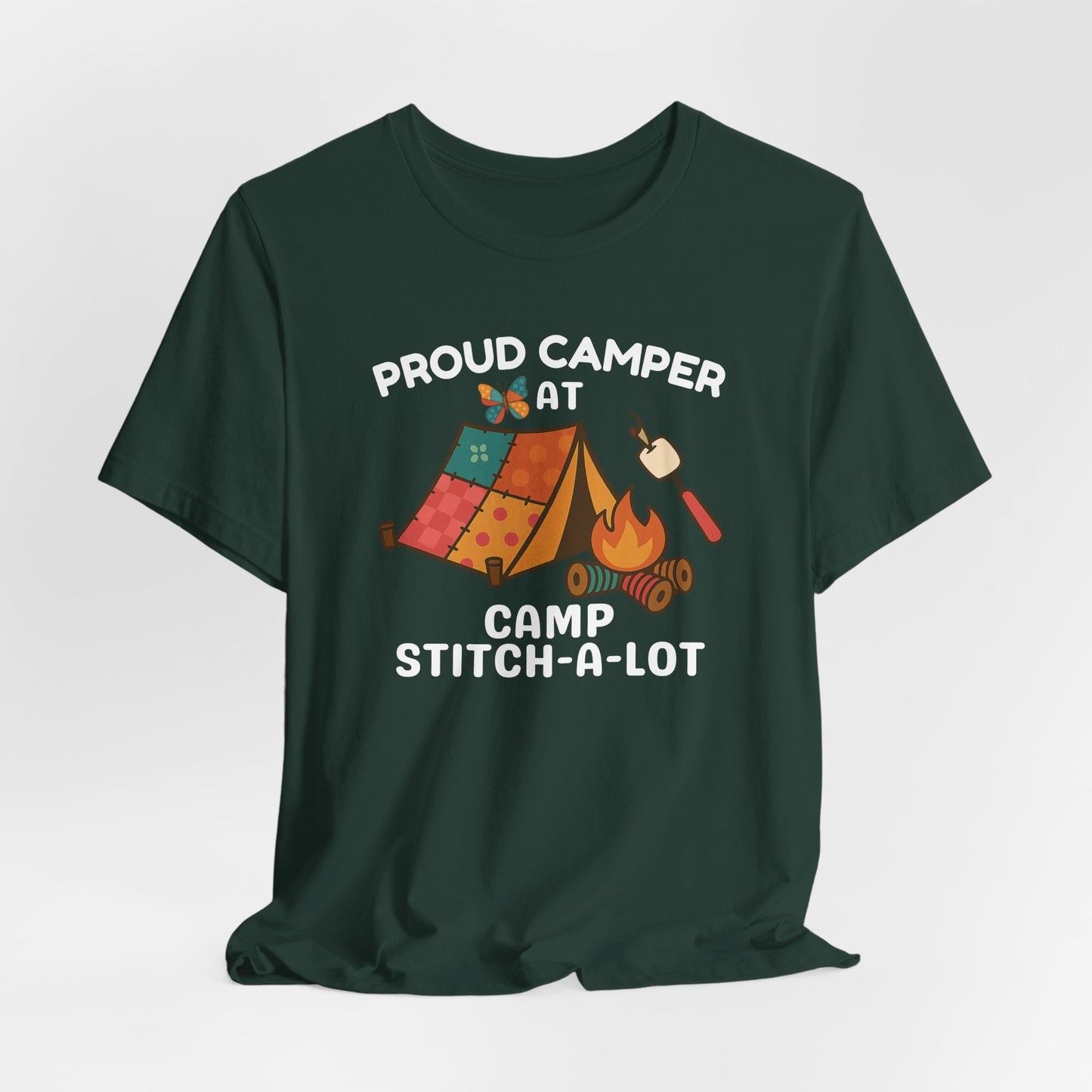 A A Forest t-shirt featuring a colorful design with a patchwork tent, thread spool campfire, marshmallow on a seam ripper stick, and a butterfly. Text reads "Proud Camper at Camp Stitch-a-Lot." Fun gift for quilting retreats.