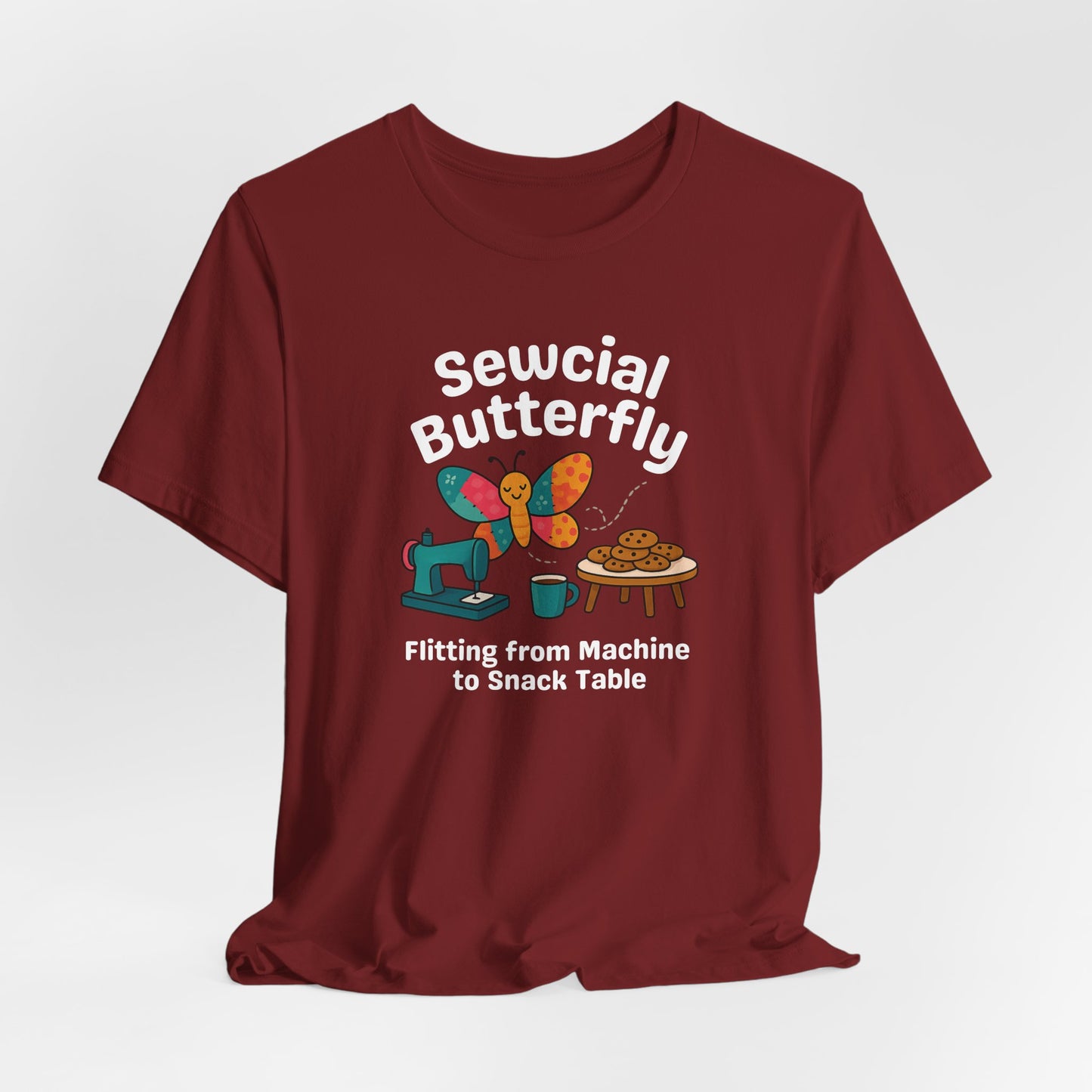 A A Cardinal t-shirt with a colorful design showing a patchwork butterfly flying between a sewing machine and a table of cookies. Text reads “Sewcial Butterfly – Flitting from Machine to Snack Table.” Funny gift for quilters
