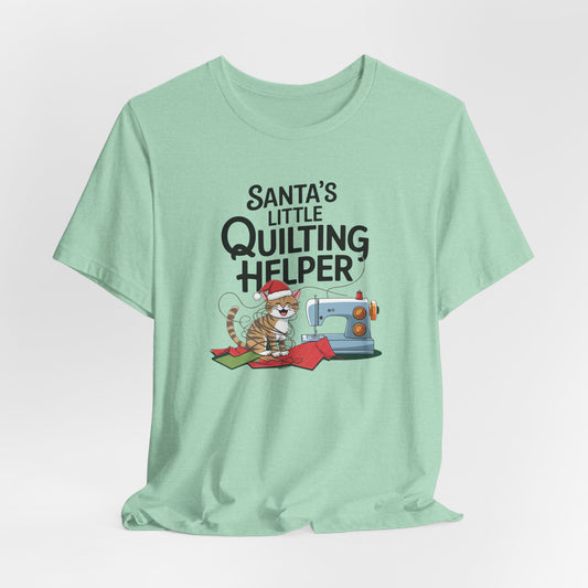 A Heather Mint christmas quilting t-shirt featuring a playful cat wearing a Santa hat is tangled in thread next to a sewing machine, with the phrase "Santa's Little Quilting Helper" above, combining quilting and holiday humor.