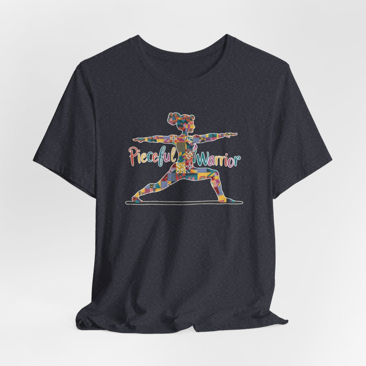 A Heather Navy Tee featuring a colorful patchwork silhouette of woman in yoga warrior pose. Text reads "Pieceful Warrior" in multicolored lettering.