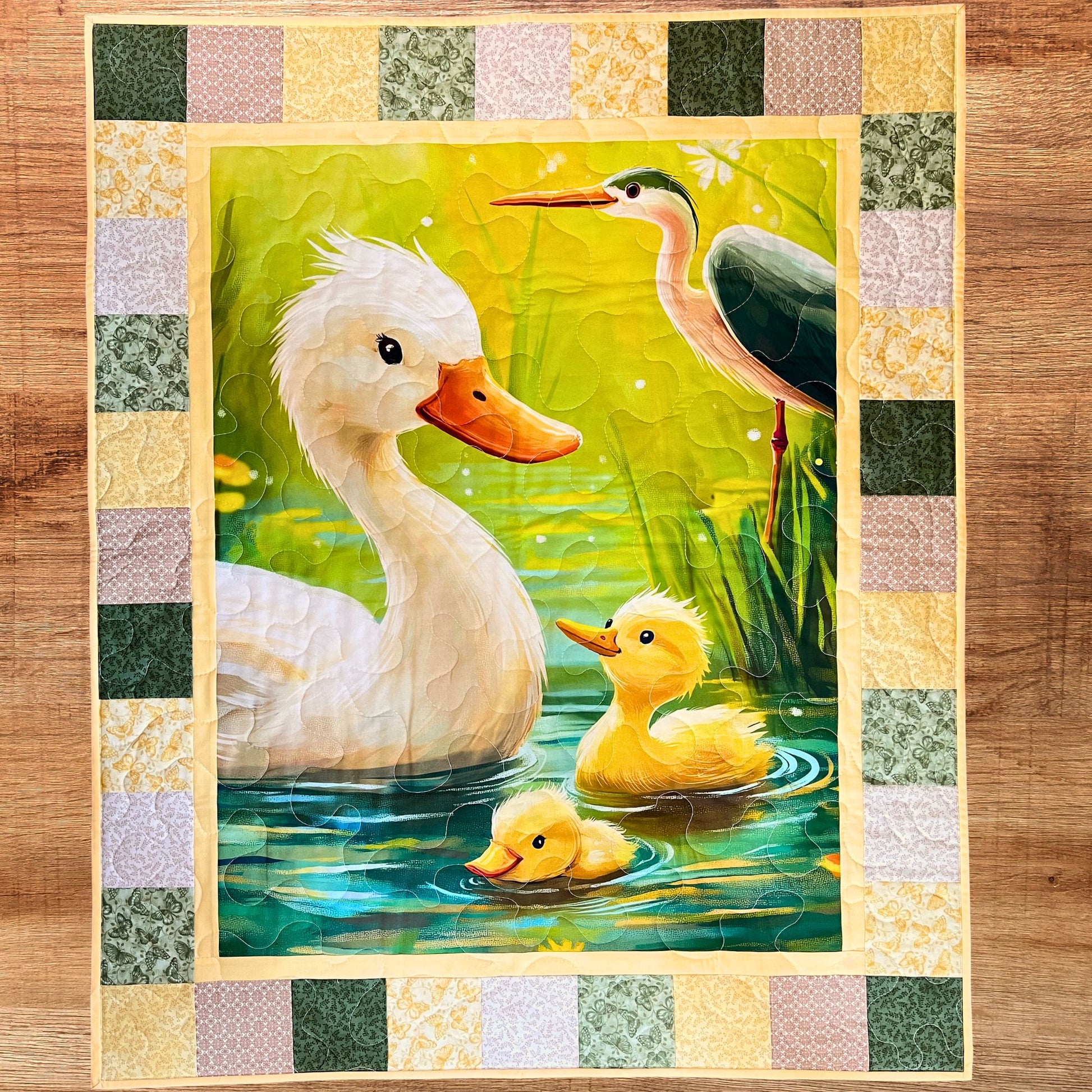 Finished Little Marsh Friends baby quilt — duck-and-ducklings pond panel framed by a checkerboard patchwork border