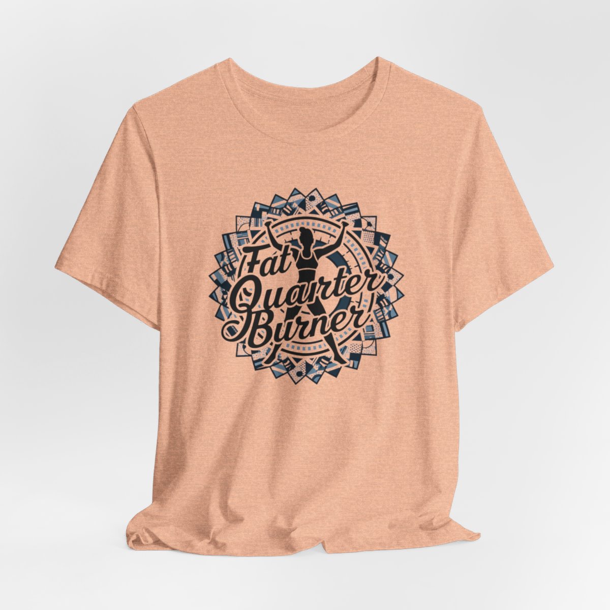 A Heather Peach T-Shirt featuring a patchwork border surrounding silhouette of woman lifting weights. Text reads "Fat Quarter Burner" in bold script.