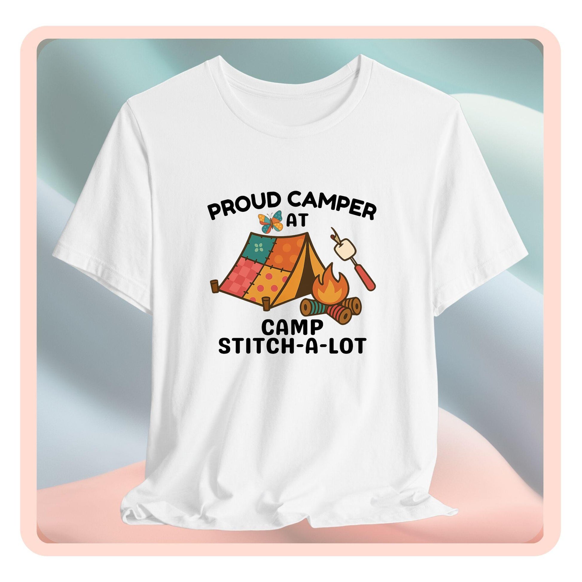 A A t-shirt featuring a colorful design with a patchwork tent, thread spool campfire, marshmallow on a seam ripper stick, and a butterfly. Text reads "Proud Camper at Camp Stitch-a-Lot." Fun gift for quilting retreats.