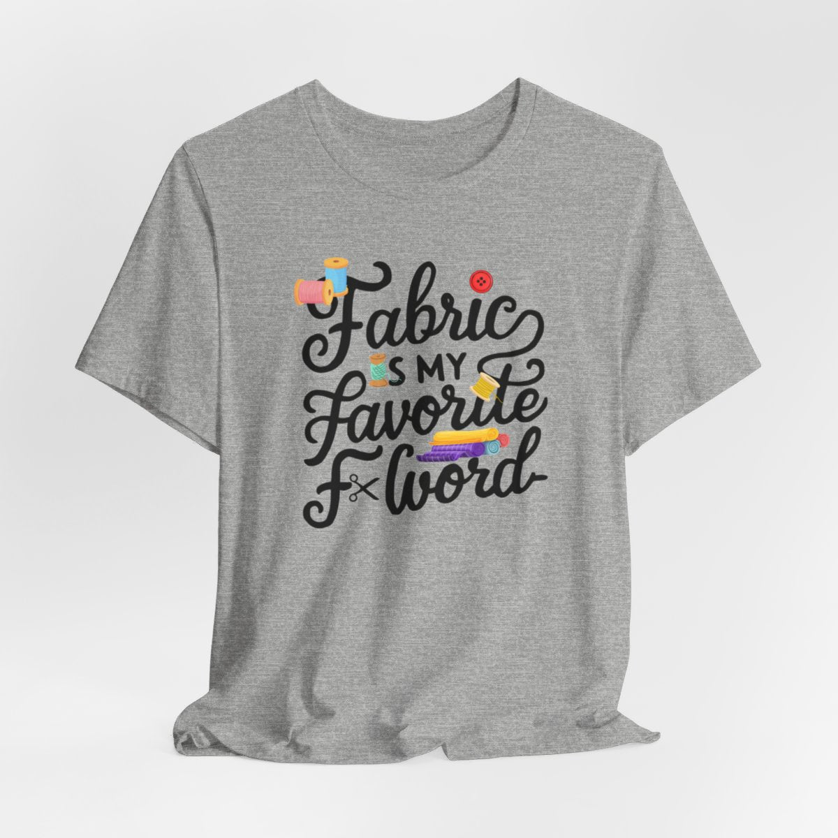An Athletic Heather T-Shirt with the phrase Fabric is My Favorite F-Word in a bold font with thread, buttons, and fabric bolts