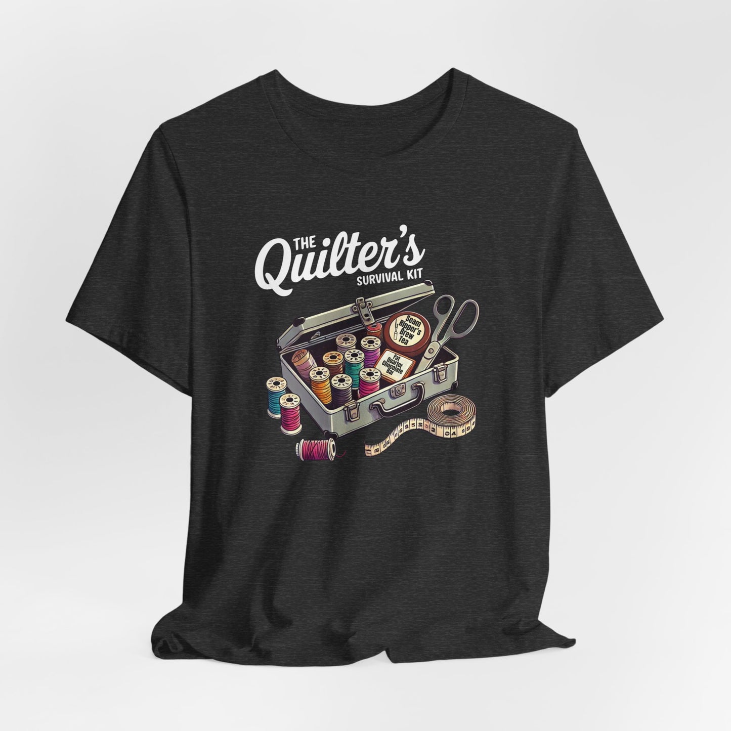 A Dark Grey Heather t-shirt featuring a whimsical illustration of a quilter’s survival kit with colorful thread spools, scissors, and a tape measure, perfect for sewing and quilting enthusiasts.