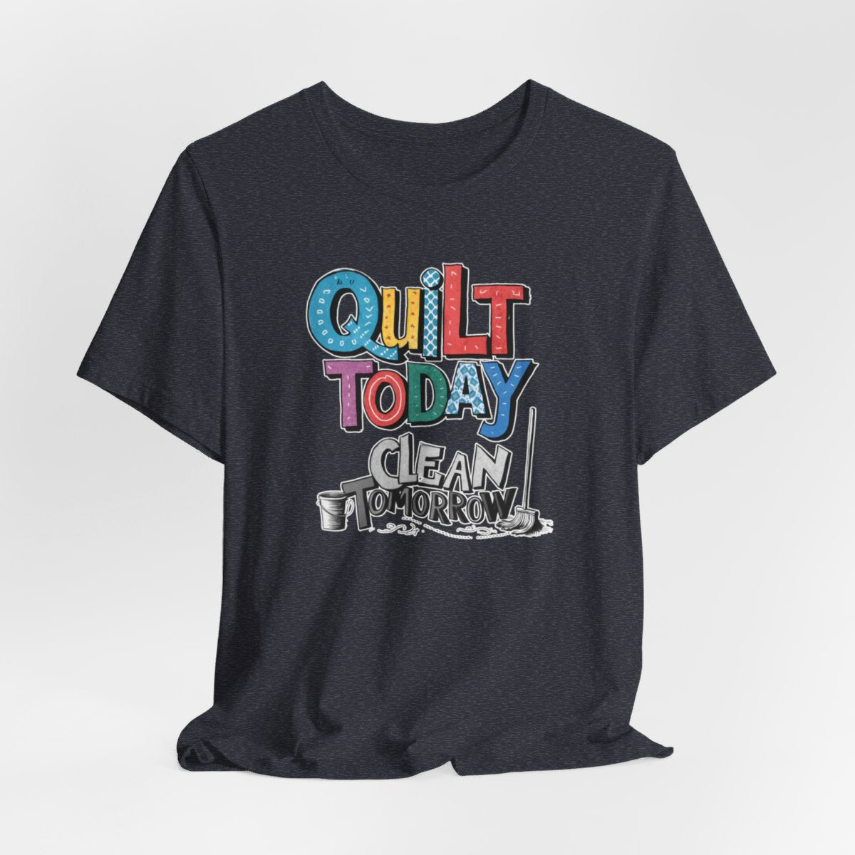 A Heather Navy funny quilting T-Shirt with the phrase Quilt Today, Clean Tomorrow in a bold and cheerful font with a broom off to the side