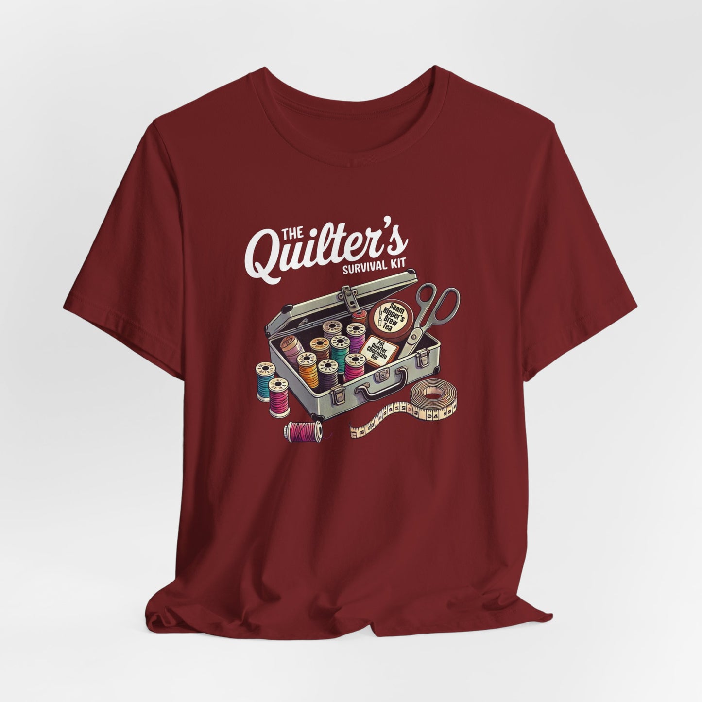 A Cardinal t-shirt featuring a whimsical illustration of a quilter’s survival kit with colorful thread spools, scissors, and a tape measure, perfect for sewing and quilting enthusiasts.