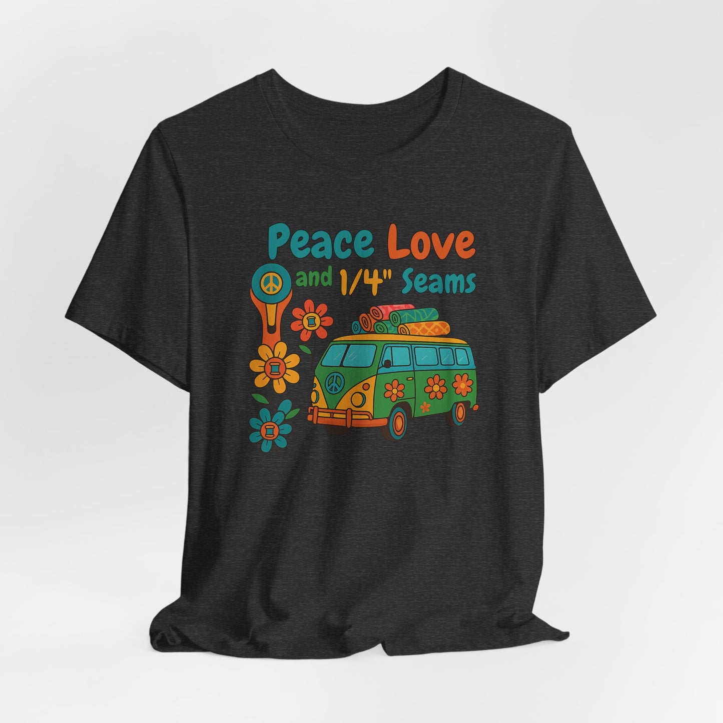 A A Dark Grey Heather t-shirt with colorful retro design showing a peace sign rotary cutter, patchwork van, and text “Peace Love and 1/4" Seams.” Surrounded by flowers made of thread spools. Fun vintage-style quilting shirt.
