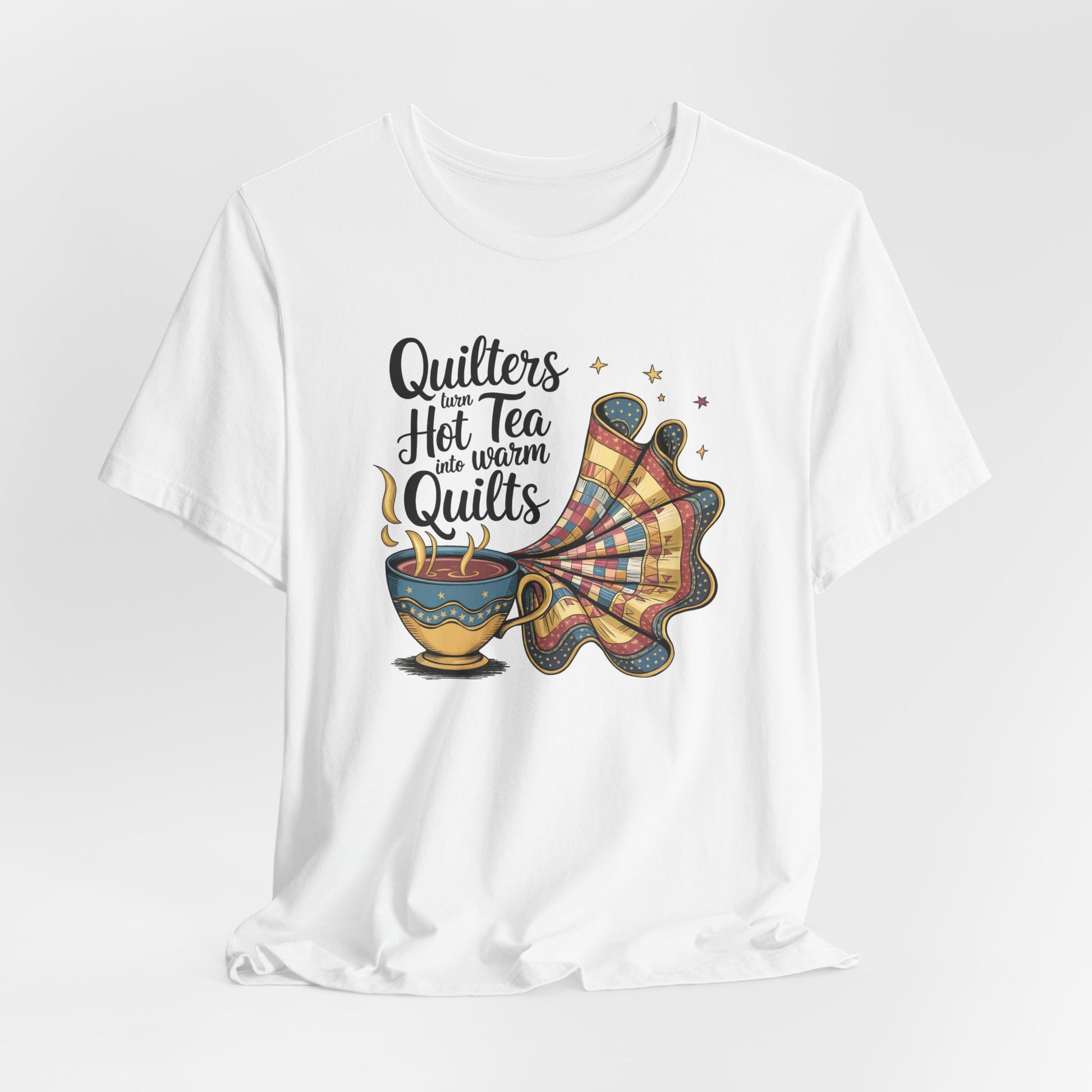 A White t-shirt with a whimsical design of a teacup transforming into a patchwork quilt, accompanied by the phrase 'Quilters turn hot tea into warm quilts.' Ideal for quilters and tea lovers