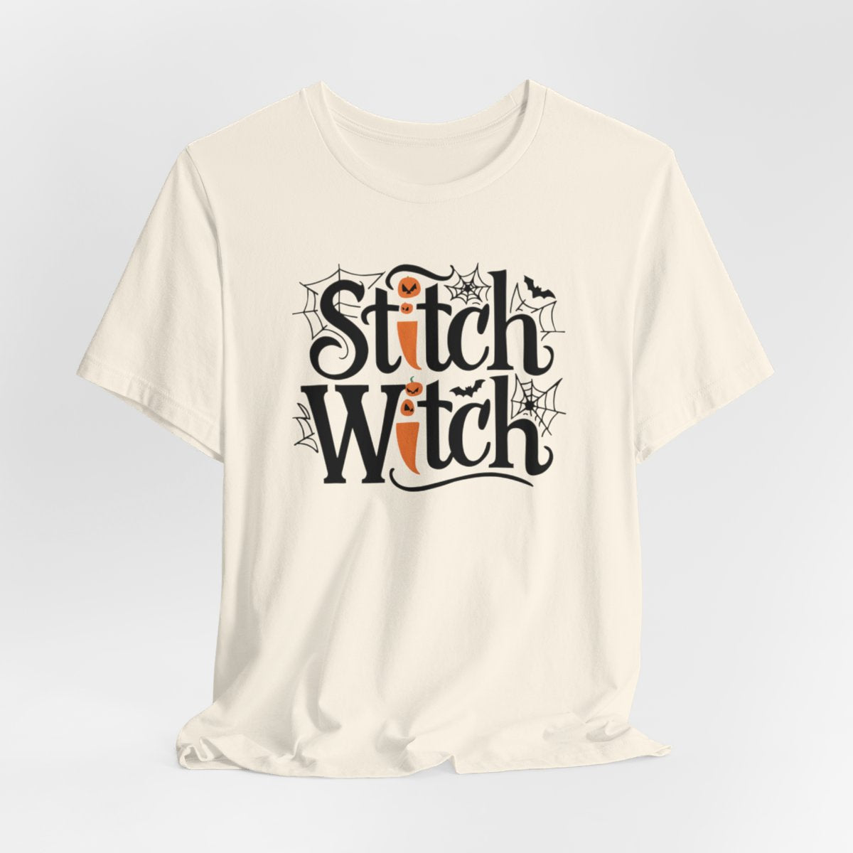 T-shirt design with "Stitch Witch" text in Halloween-themed typography. Jack-o'-lanterns, spiderwebs, and bats decorate the letters. The "i" in "Stitch" resembles a sewing needle. Ideal for quilters who love Halloween.
