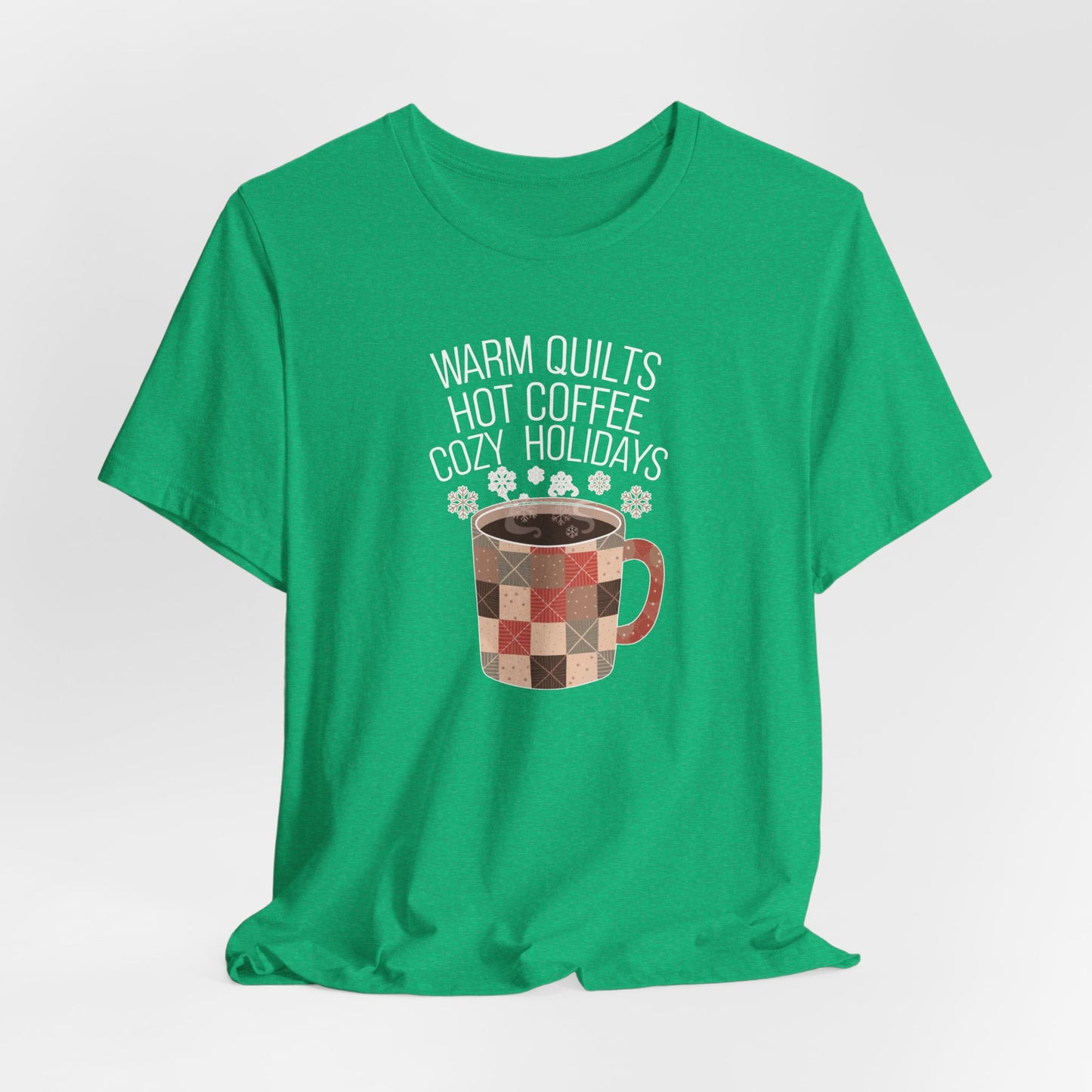 A Heather Kelly christmas quilting t-shirt featuring a cozy patchwork quilt-themed coffee mug, surrounded by snowflakes, with the phrase "Warm Quilts, Hot Coffee, Cozy Holidays" above the mug, celebrating the warmth of quilts and coffee during the holiday season.