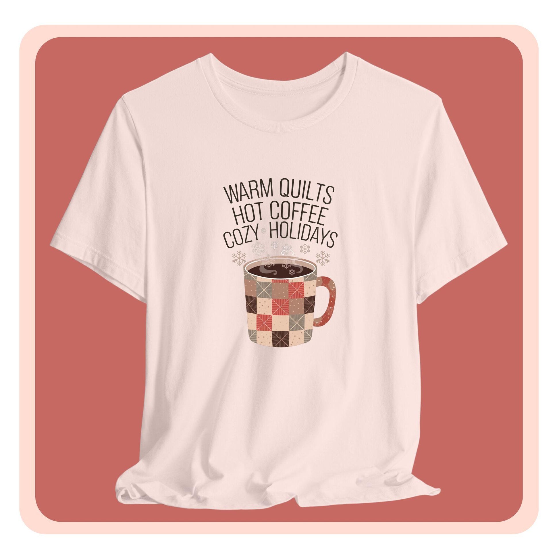 A christmas quilting t-shirt featuring a cozy patchwork quilt-themed coffee mug, surrounded by snowflakes, with the phrase "Warm Quilts, Hot Coffee, Cozy Holidays" above the mug, celebrating the warmth of quilts and coffee during the holiday season.