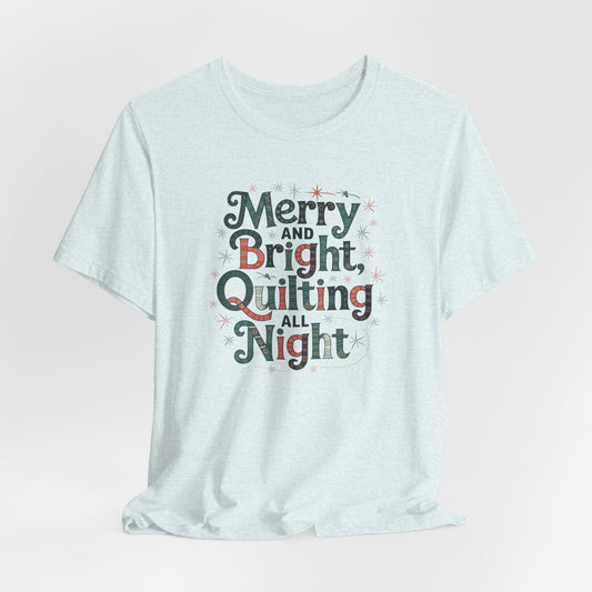 A Heather Ice Blue christmas quilting T-shirt featuring a whimsical design with the phrase "Merry and Bright, Quilting All Night," featuring festive quilting patterns and holiday-themed elements like stars and stitching lines.  Perfect gift for quilters.