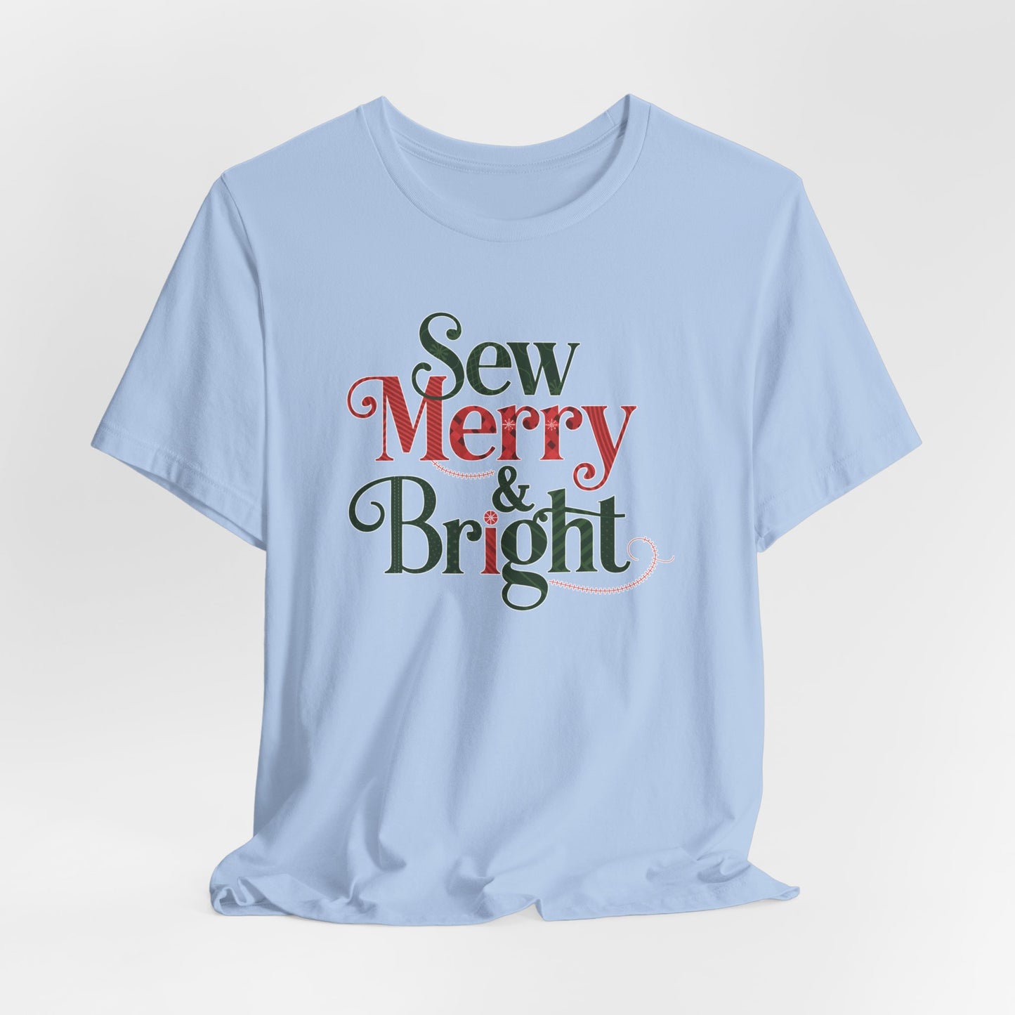 A Baby Blue t-shirt with the phrase "Sew Merry & Bright," incorporating sewing-inspired elements and holiday-themed accents, such as stitching lines and festive patterns.