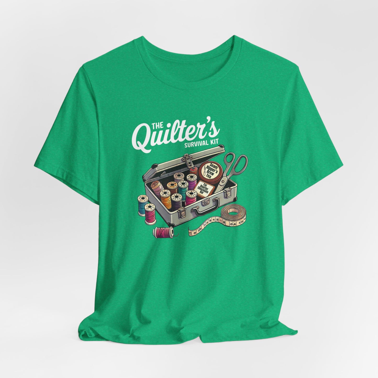 A Heather Kelly t-shirt featuring a whimsical illustration of a quilter’s survival kit with colorful thread spools, scissors, and a tape measure, perfect for sewing and quilting enthusiasts.