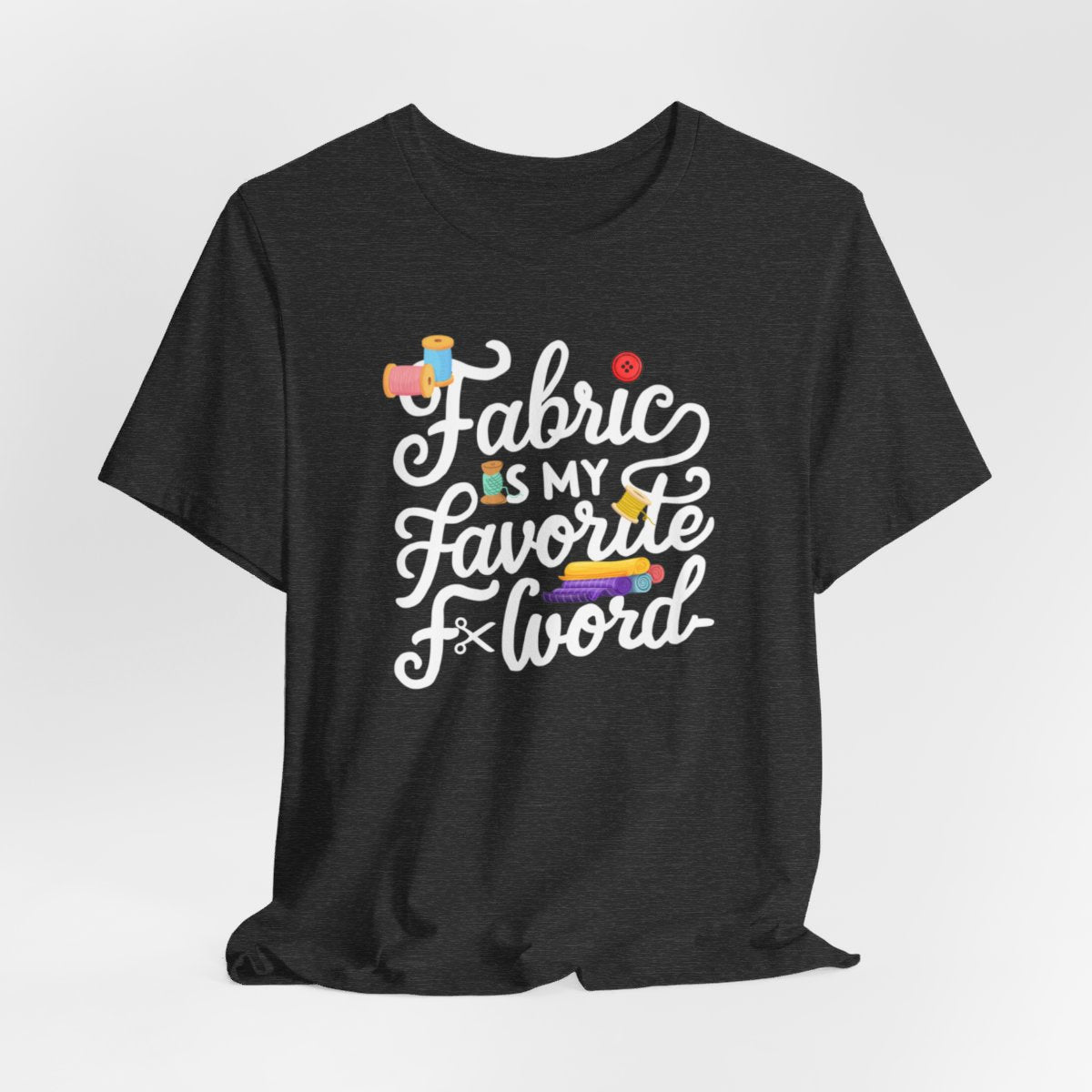 A Dark Grey Heather T-Shirt with the phrase Fabric is My Favorite F-Word in a bold font with thread, buttons, and fabric bolts