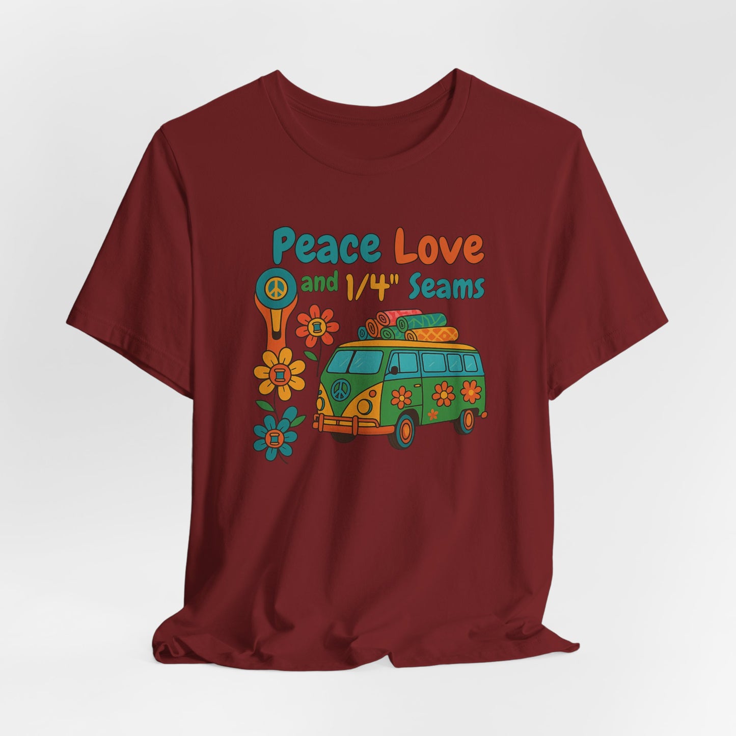 A A Cardinal t-shirt with colorful retro design showing a peace sign rotary cutter, patchwork van, and text “Peace Love and 1/4" Seams.” Surrounded by flowers made of thread spools. Fun vintage-style quilting shirt.