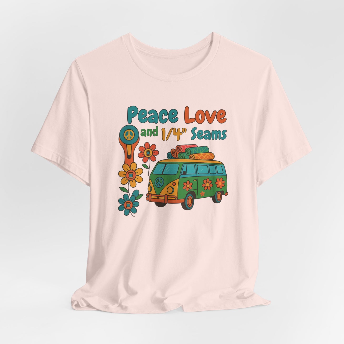 A A Soft Pink t-shirt with colorful retro design showing a peace sign rotary cutter, patchwork van, and text “Peace Love and 1/4" Seams.” Surrounded by flowers made of thread spools. Fun vintage-style quilting shirt.