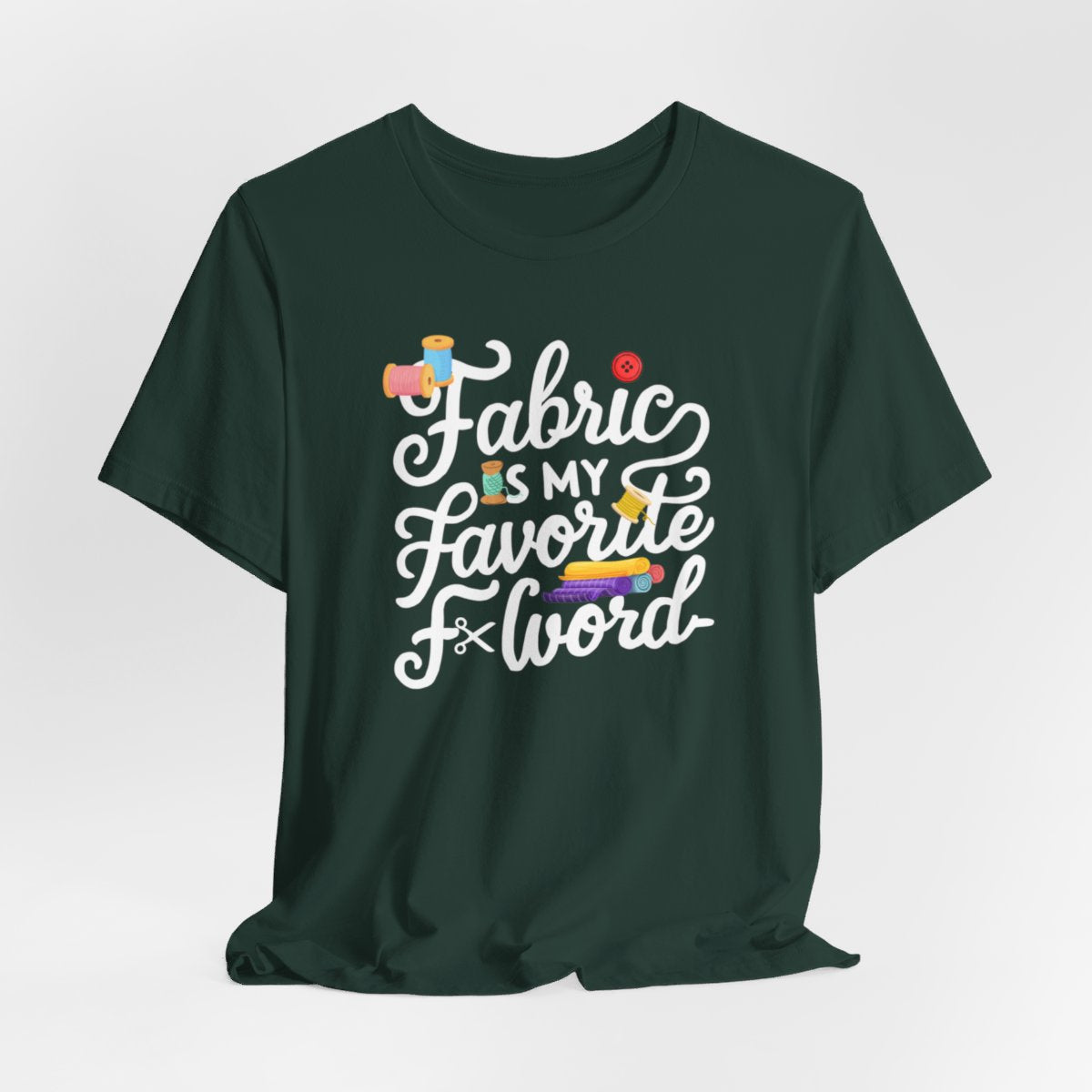A Forest T-Shirt with the phrase Fabric is My Favorite F-Word in a bold font with thread, buttons, and fabric bolts