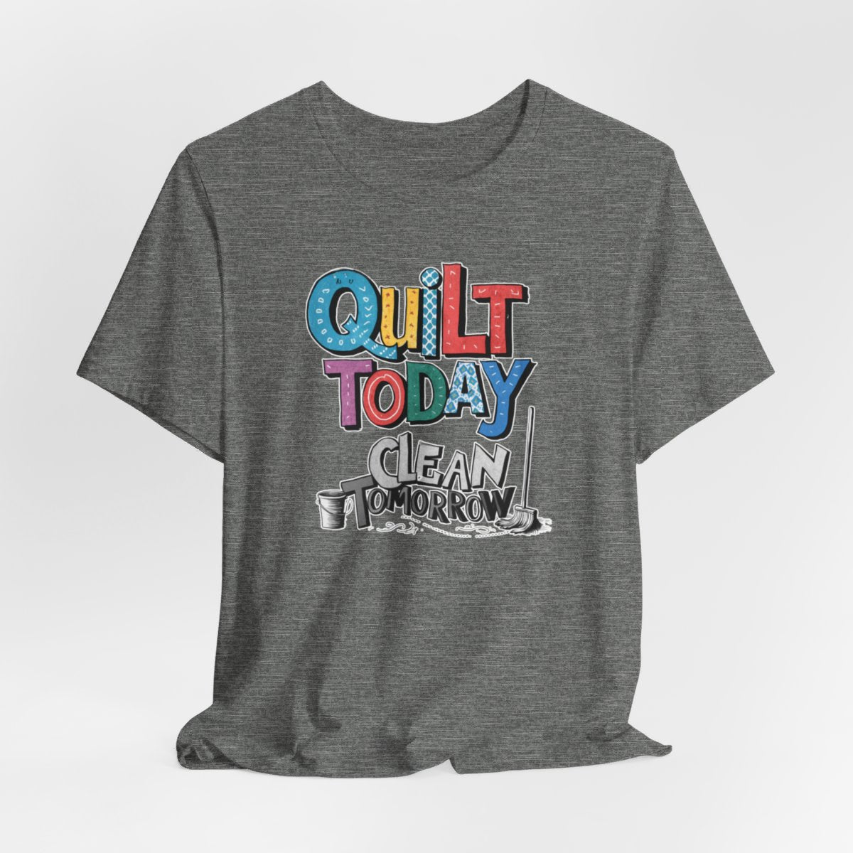A Deep Heather funny quilting T-Shirt with the phrase Quilt Today, Clean Tomorrow in a bold and cheerful font with a broom off to the side