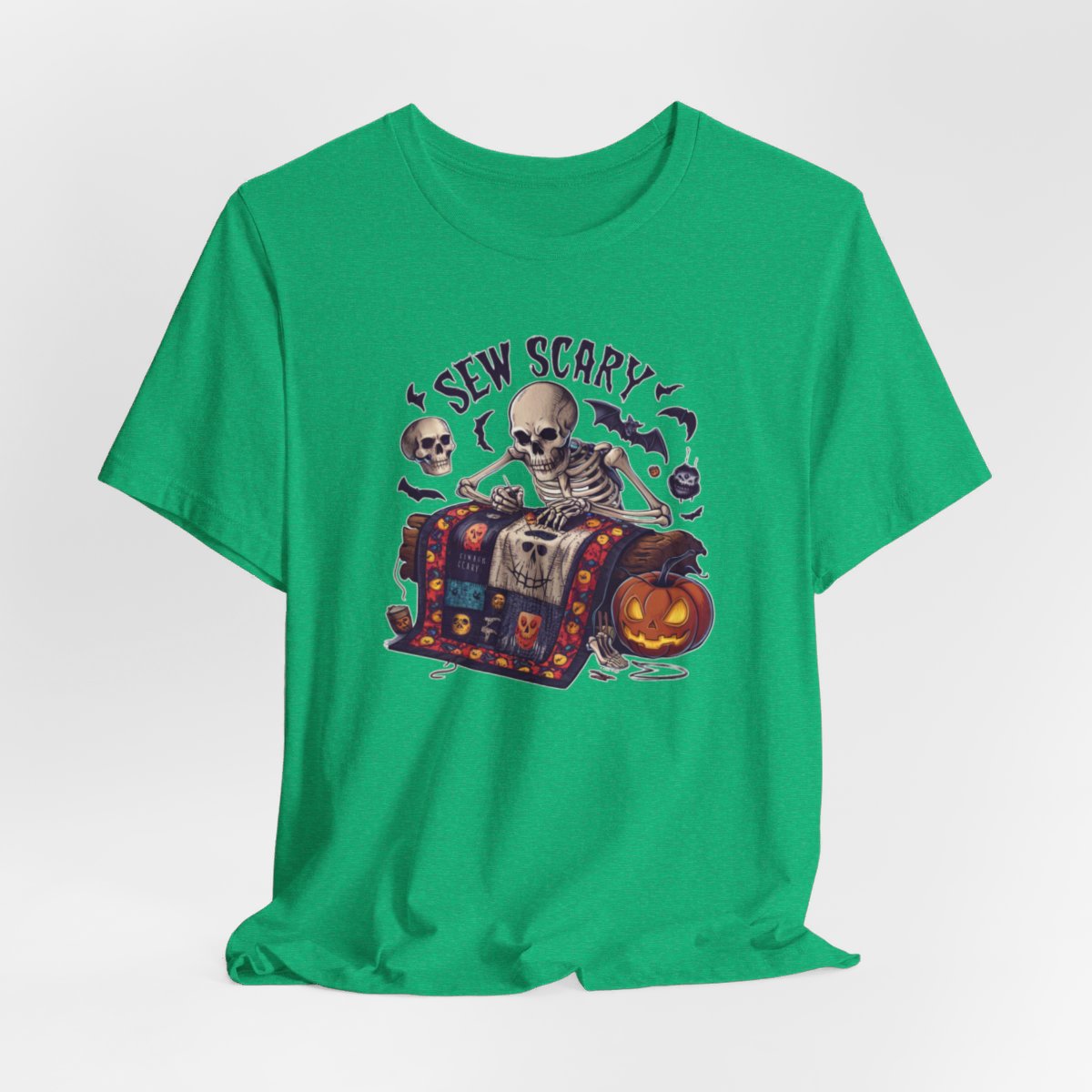 A Heather Kelly Halloween Quilting T-Shirt featuring a skeleton sewing Halloween quilt. Colorful patchwork with spooky motifs. Bats and pumpkins surround skeleton. Text reads "Sew Scary". Ideal for quilters who love Halloween.