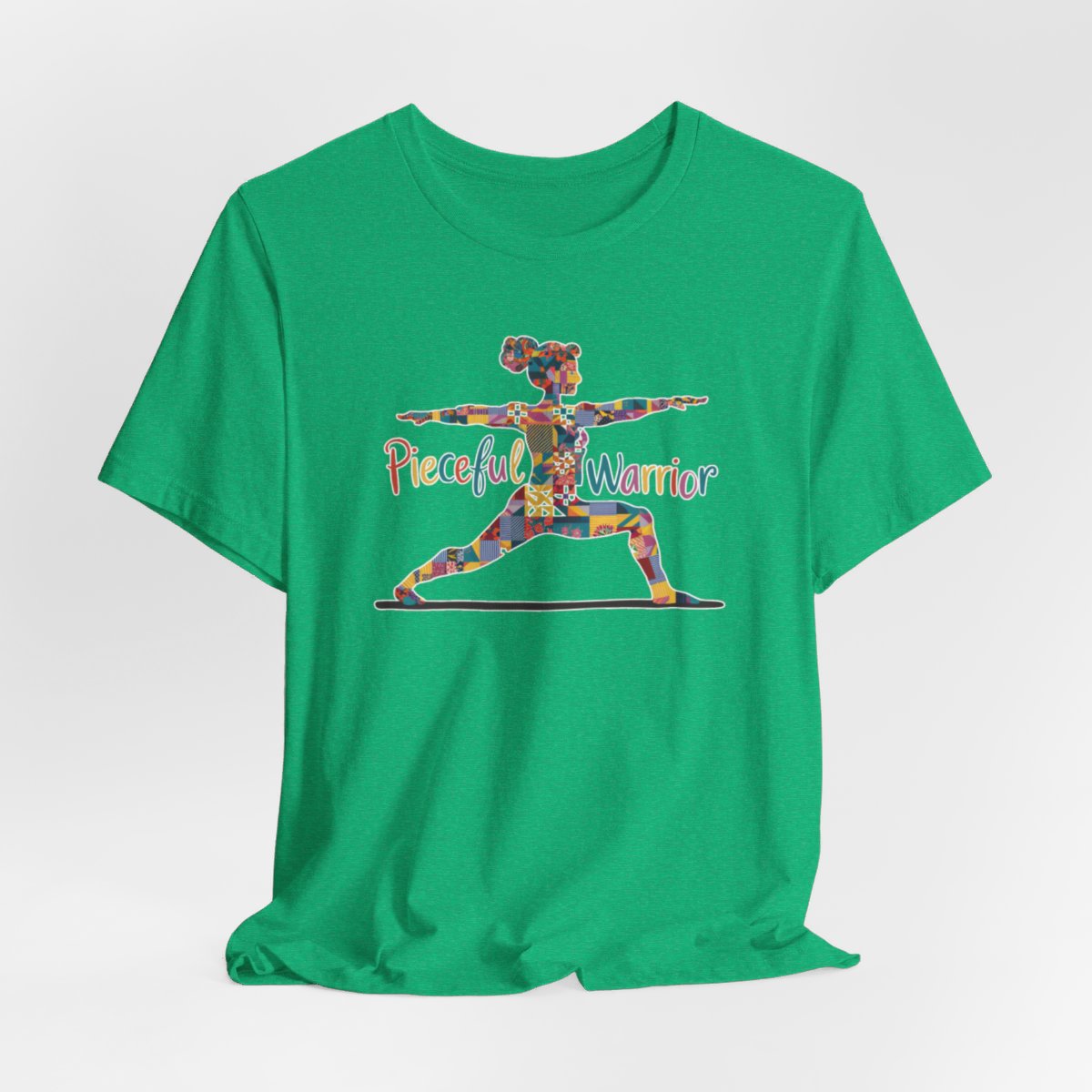 A Heather Kelly Tee featuring a colorful patchwork silhouette of woman in yoga warrior pose. Text reads "Pieceful Warrior" in multicolored lettering.