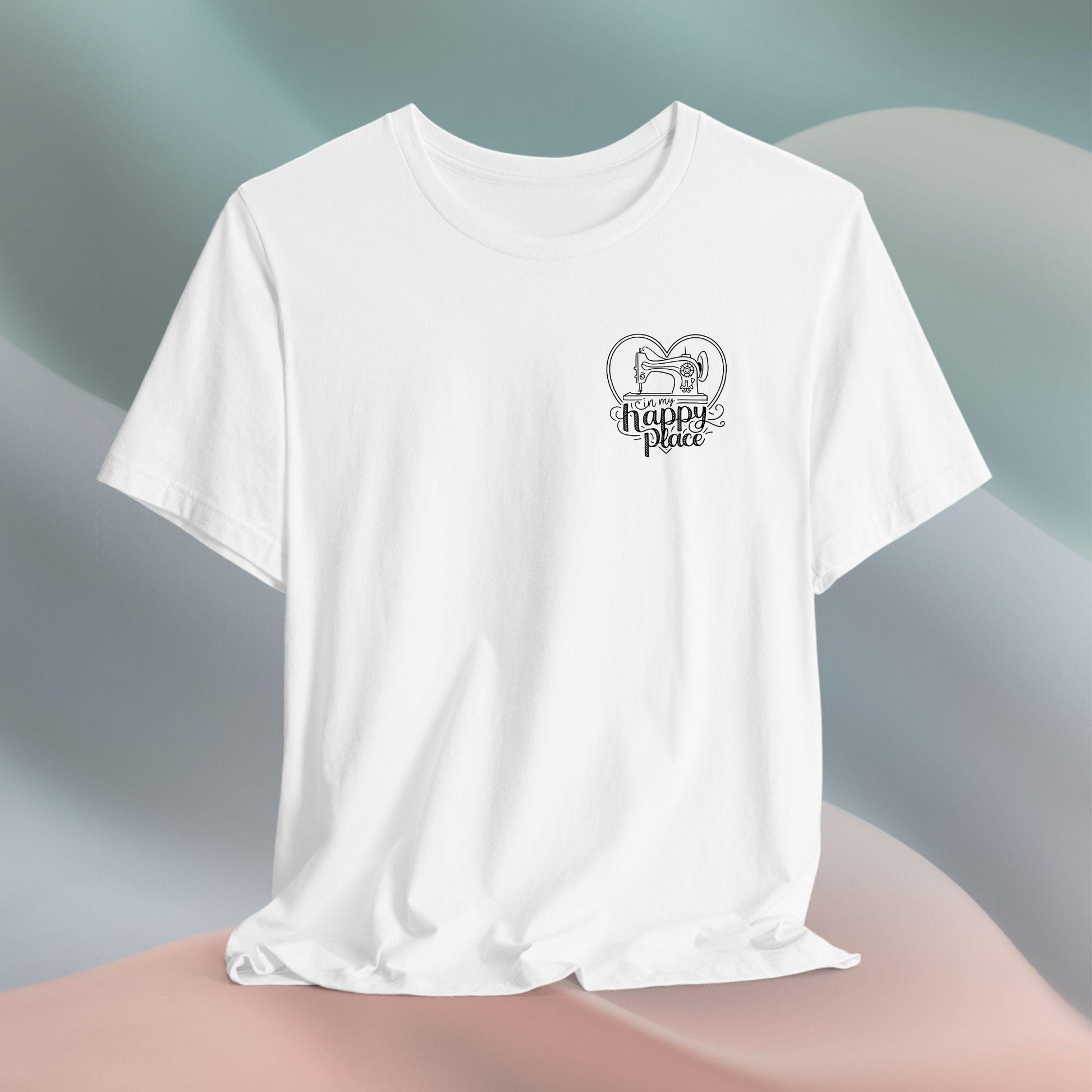 A funny quilting T-shirt design showing a sewing machine inside a heart shape with decorative swirls. Text reads "In my happy place" in mixed fonts, emphasizing quilting as a source of joy and contentment for enthusiasts.