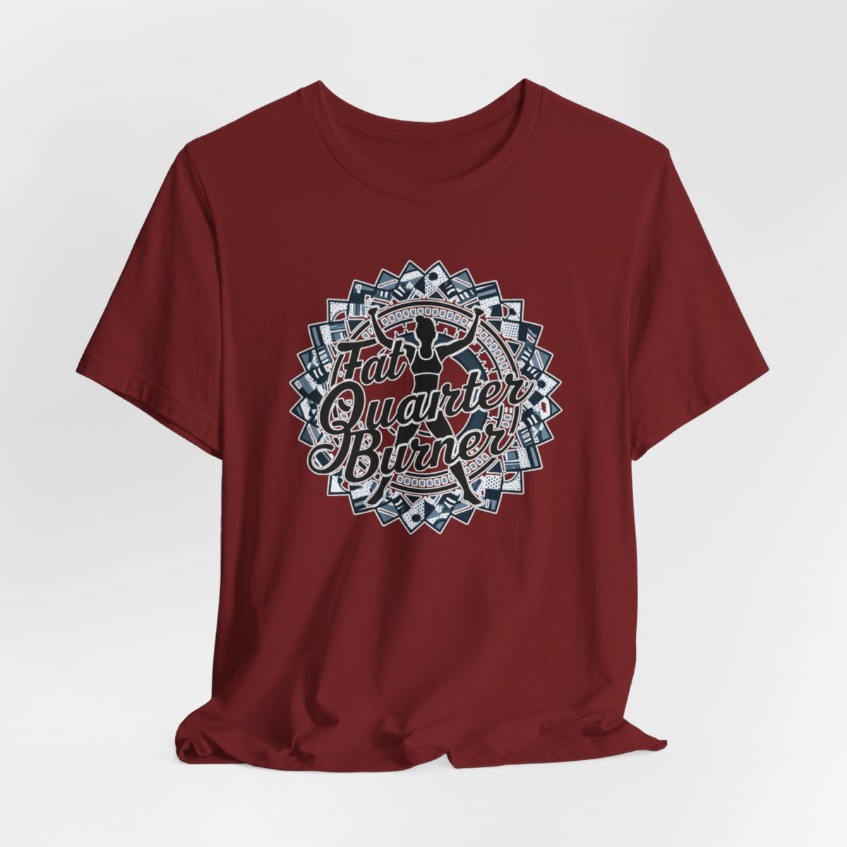 A Cardinal T-Shirt featuring a patchwork border surrounding silhouette of woman lifting weights. Text reads "Fat Quarter Burner" in bold script.
