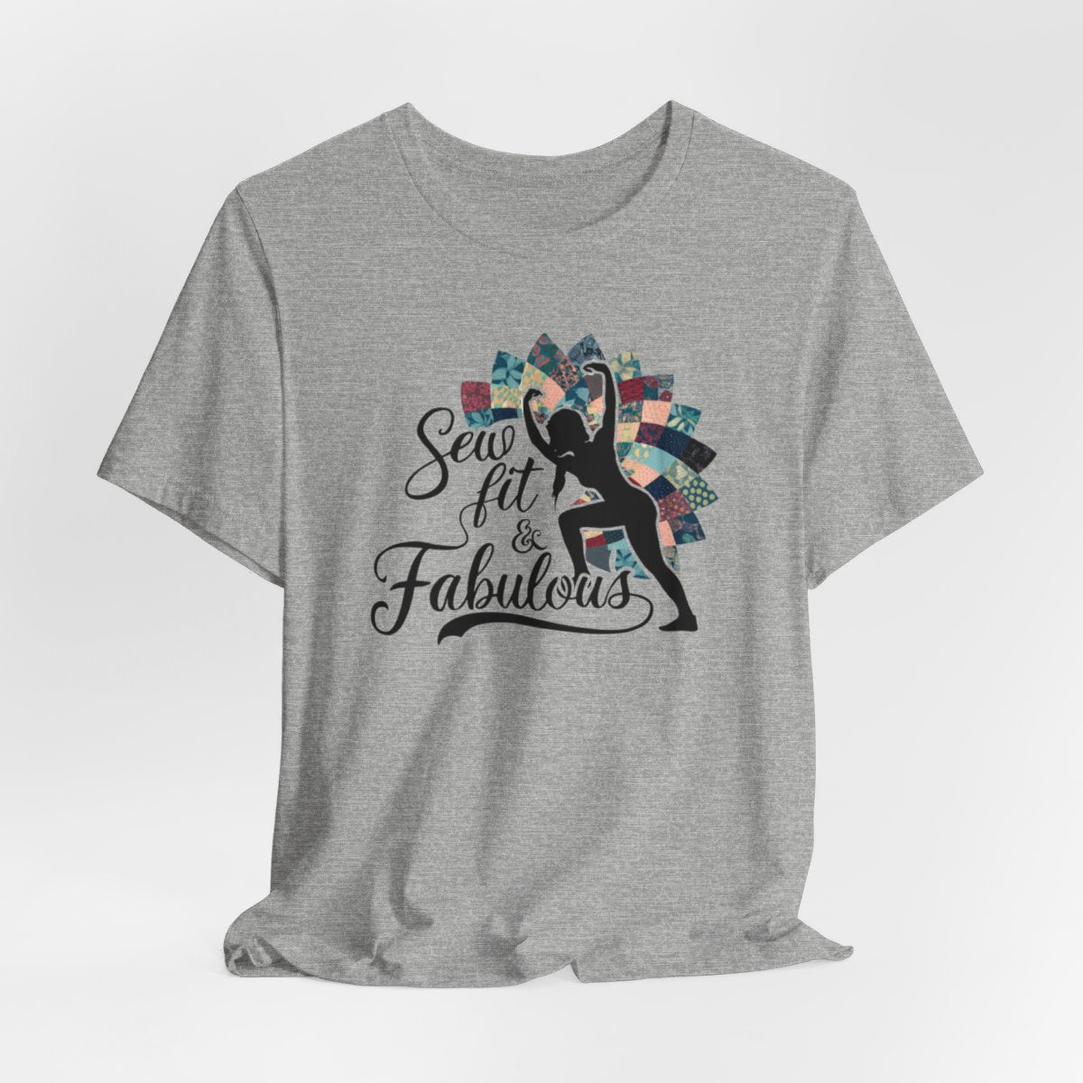 An Athletic Heather T-Shirt featuring a black silhouette of woman with raised arms against colorful patchwork background. Text reads "Sew fit & Fabulous" in stylized script.