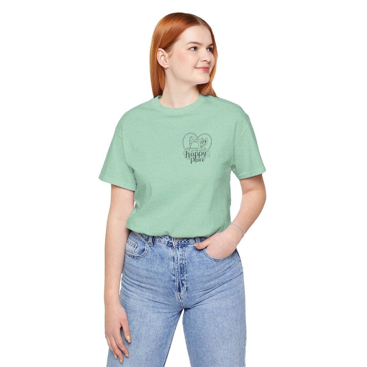 A Heather Mint funny quilting T-shirt design showing a sewing machine inside a heart shape with decorative swirls. Text reads "In my happy place" in mixed fonts, emphasizing quilting as a source of joy and contentment for enthusiasts.