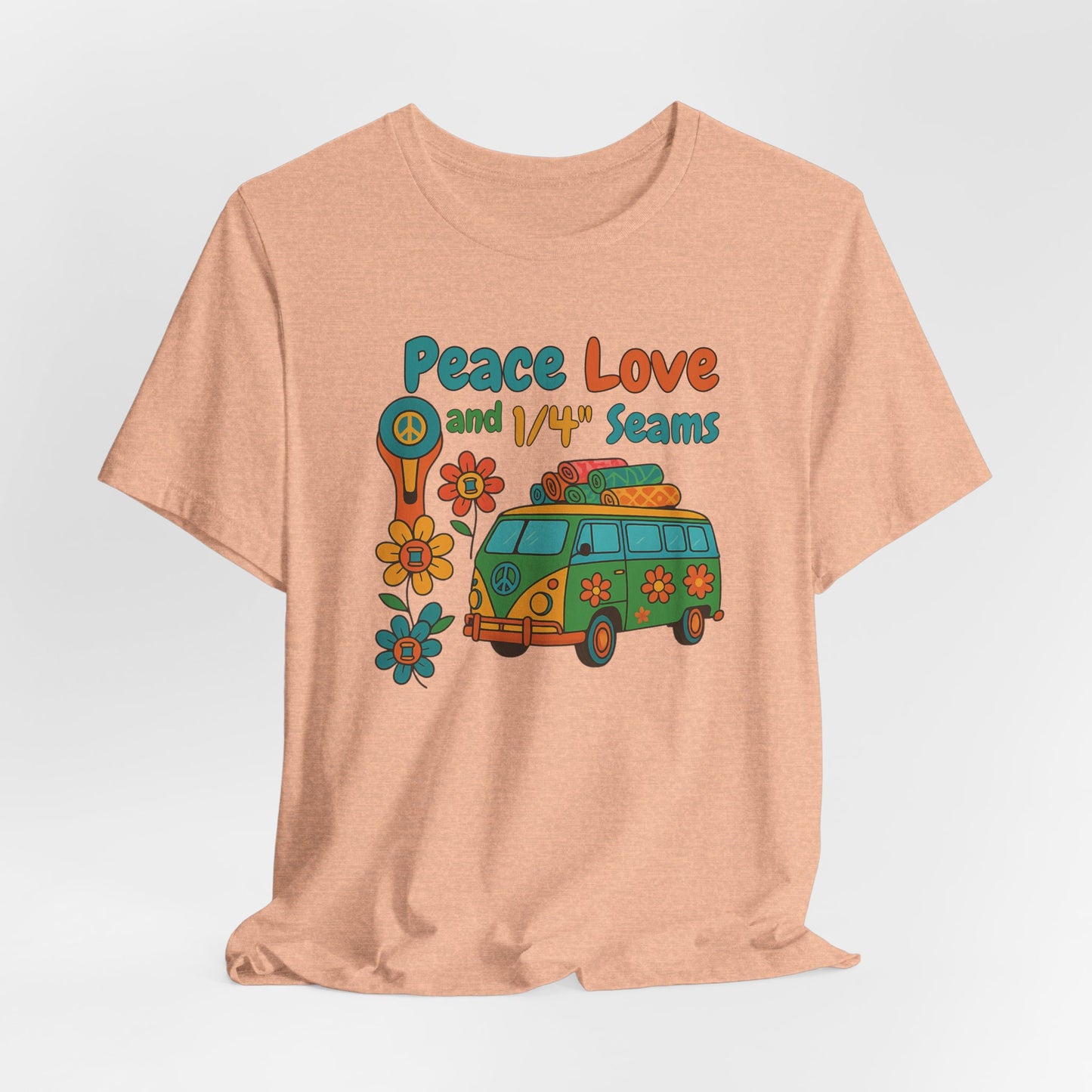 A A Heather Peach t-shirt with colorful retro design showing a peace sign rotary cutter, patchwork van, and text “Peace Love and 1/4" Seams.” Surrounded by flowers made of thread spools. Fun vintage-style quilting shirt.