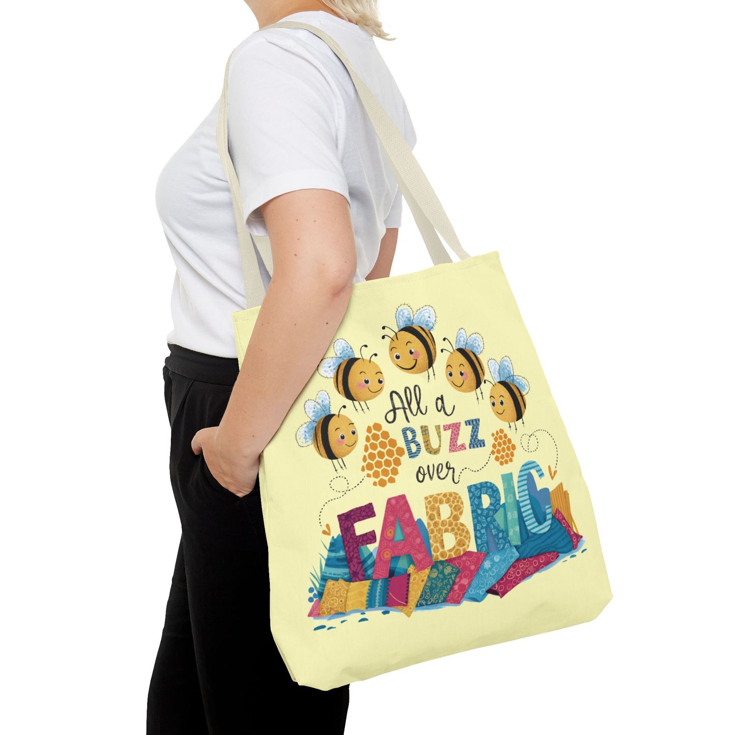 A quilting tote bag with a delightful quilting theme. Get ready to be all a buzz with excitement over your fabric stash! This playful "All a Buzz Over Fabric" 18" x 18" tote bag features adorable cartoon bees buzzing over a colorful pile of fabric, capturing the joy every quilter and sewer feels when surrounded by fabric goodness. Available in both light blue and light yellow, this cheerful design is perfect for carrying your fabric finds, sewing supplies, or everyday essentials.